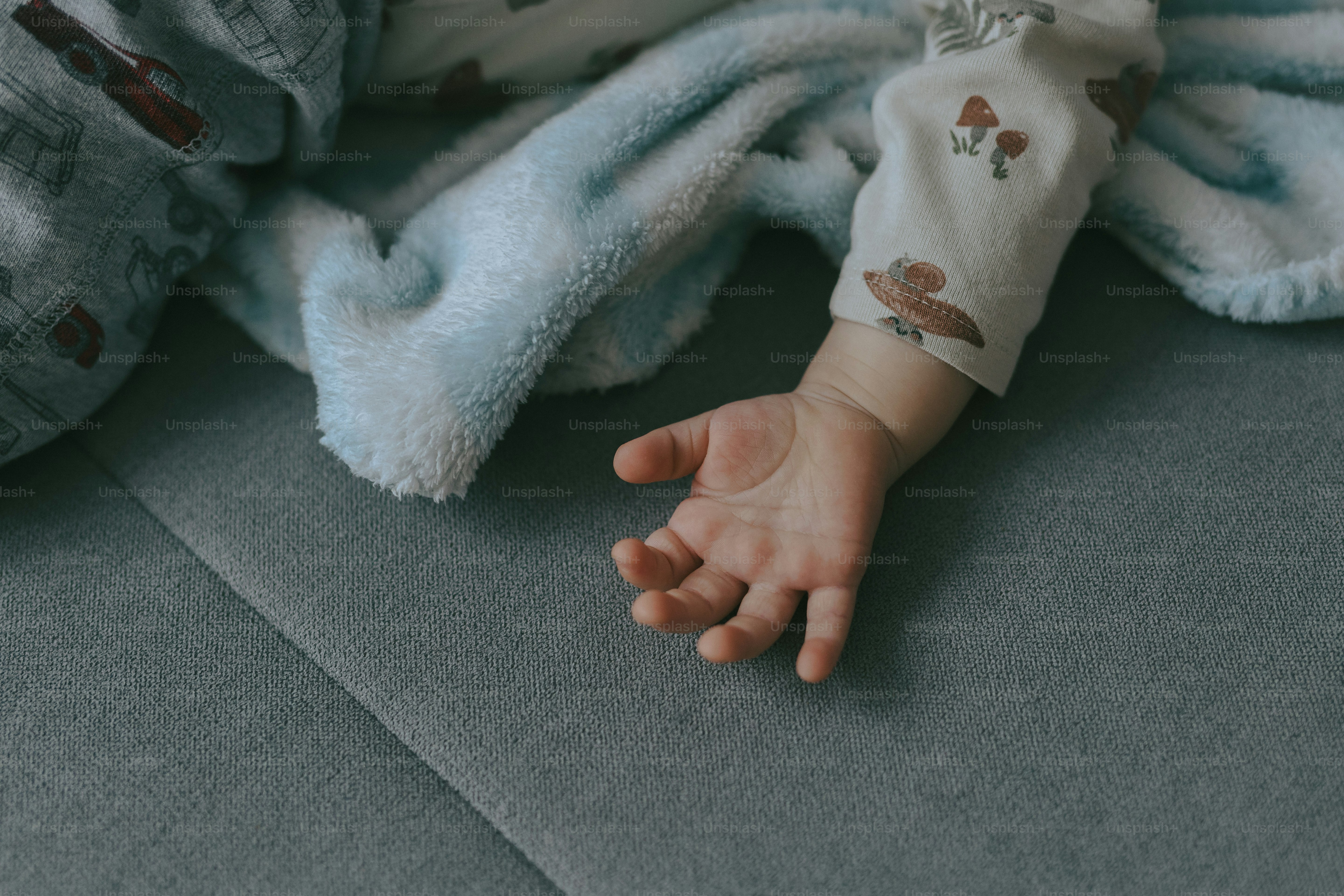 A baby wrapped in a blanket laying on a couch