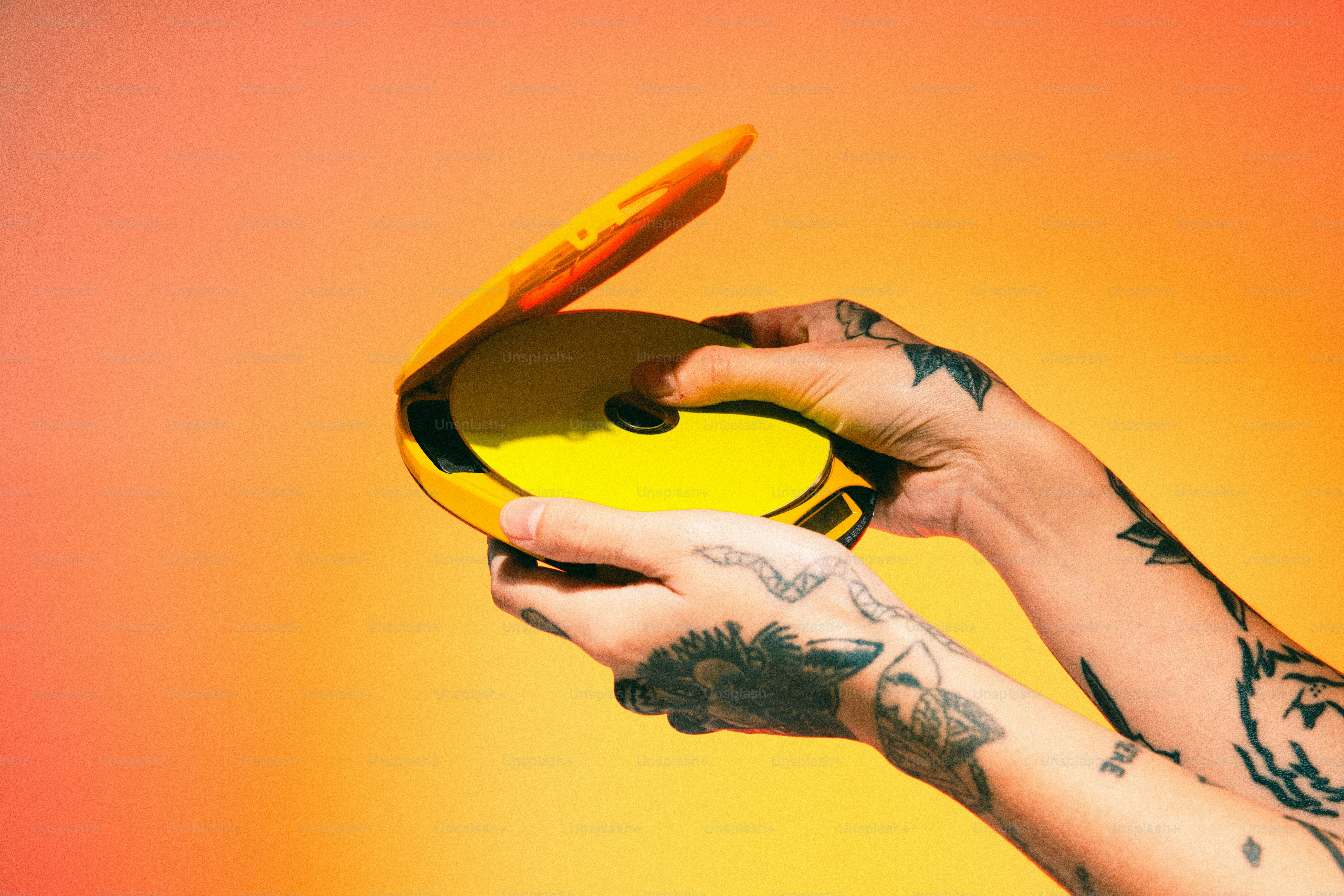 Uma pessoa com tatuagens segurando um frisbee amarelo