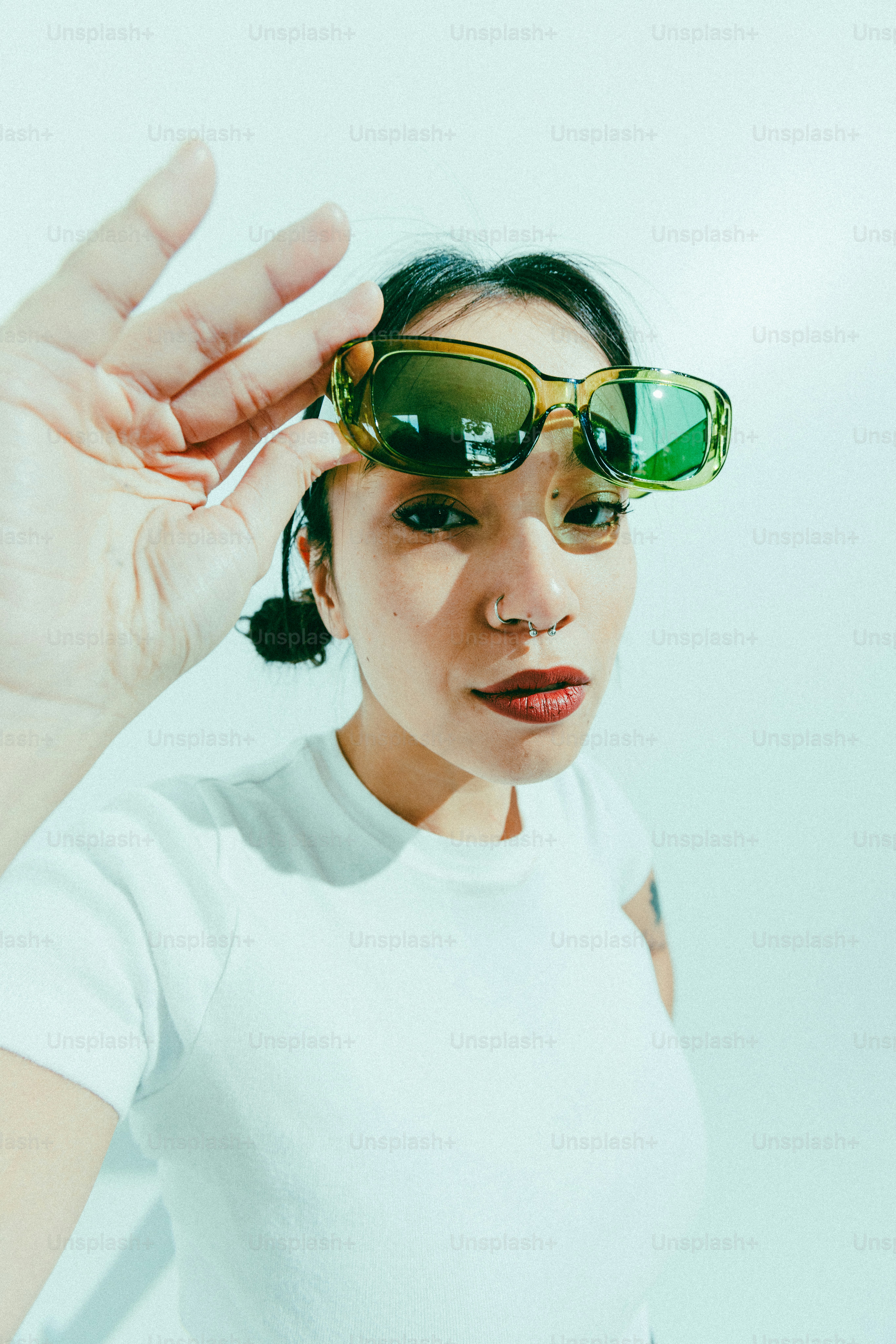 A woman in a white shirt and green sunglasses