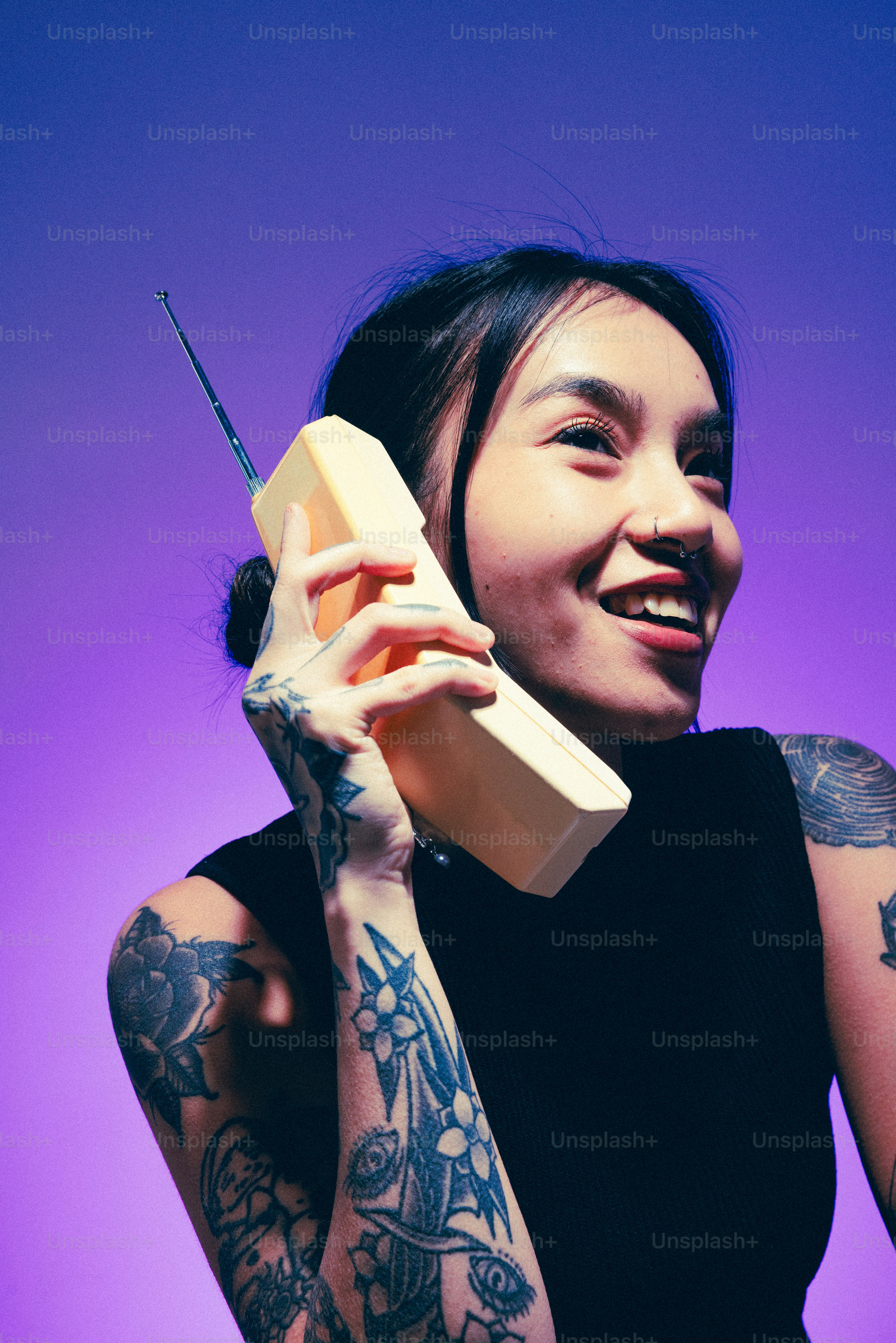 Seorang wanita dengan tato memegang telepon ke telinganya