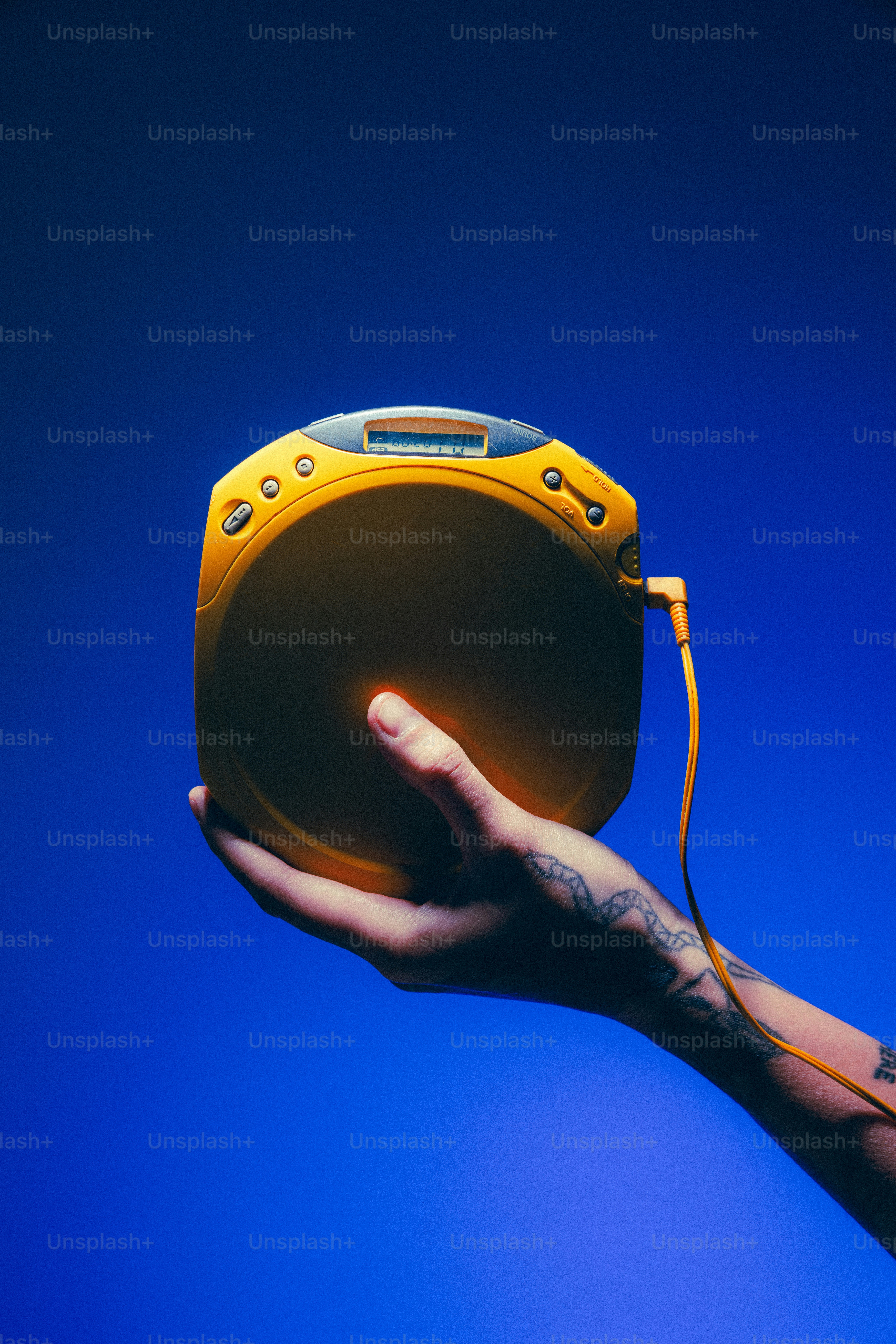 A person holding a yellow speaker in their hand