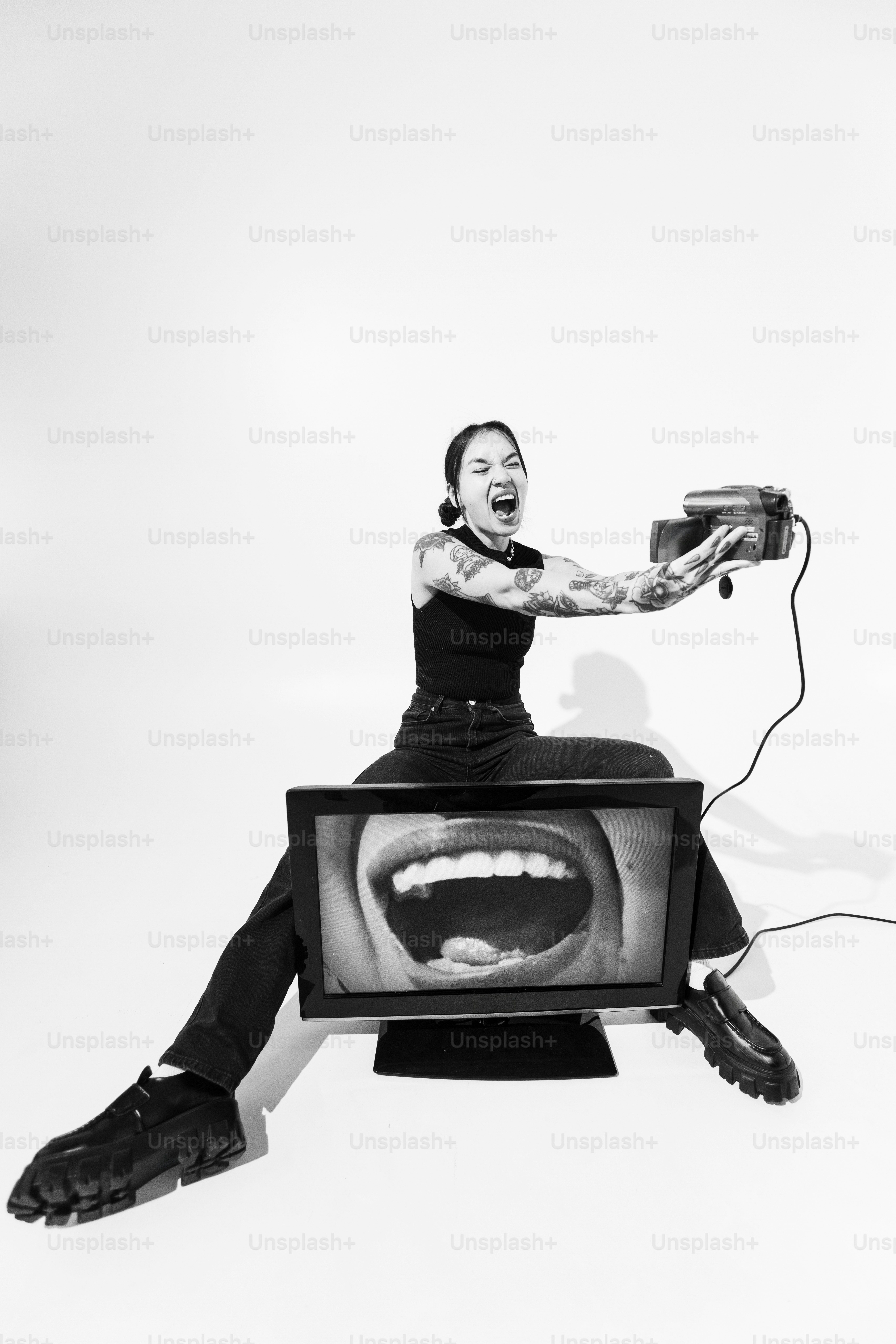 A woman sitting on top of a TV holding a remote