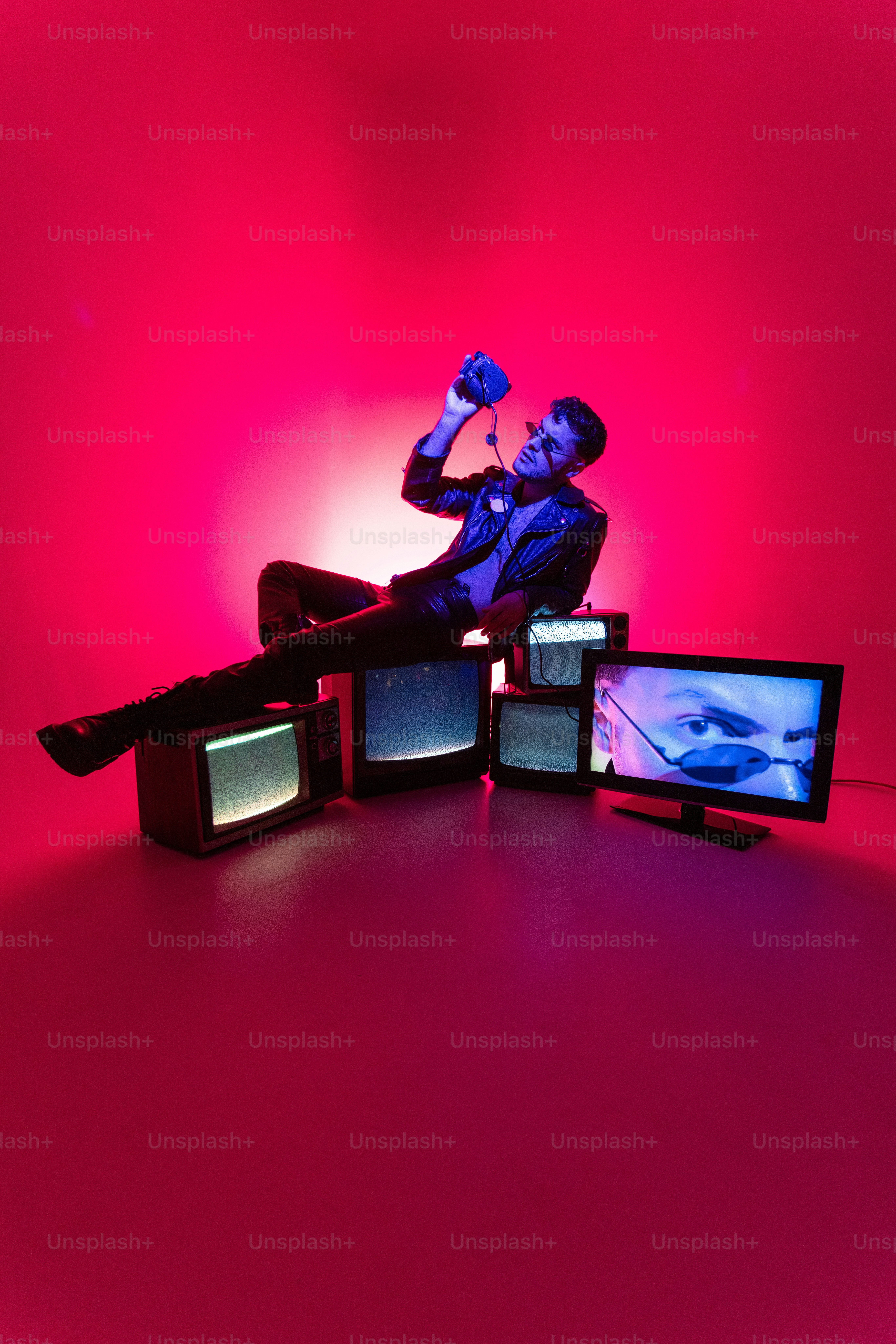 A man sitting on top of a table next to tvs