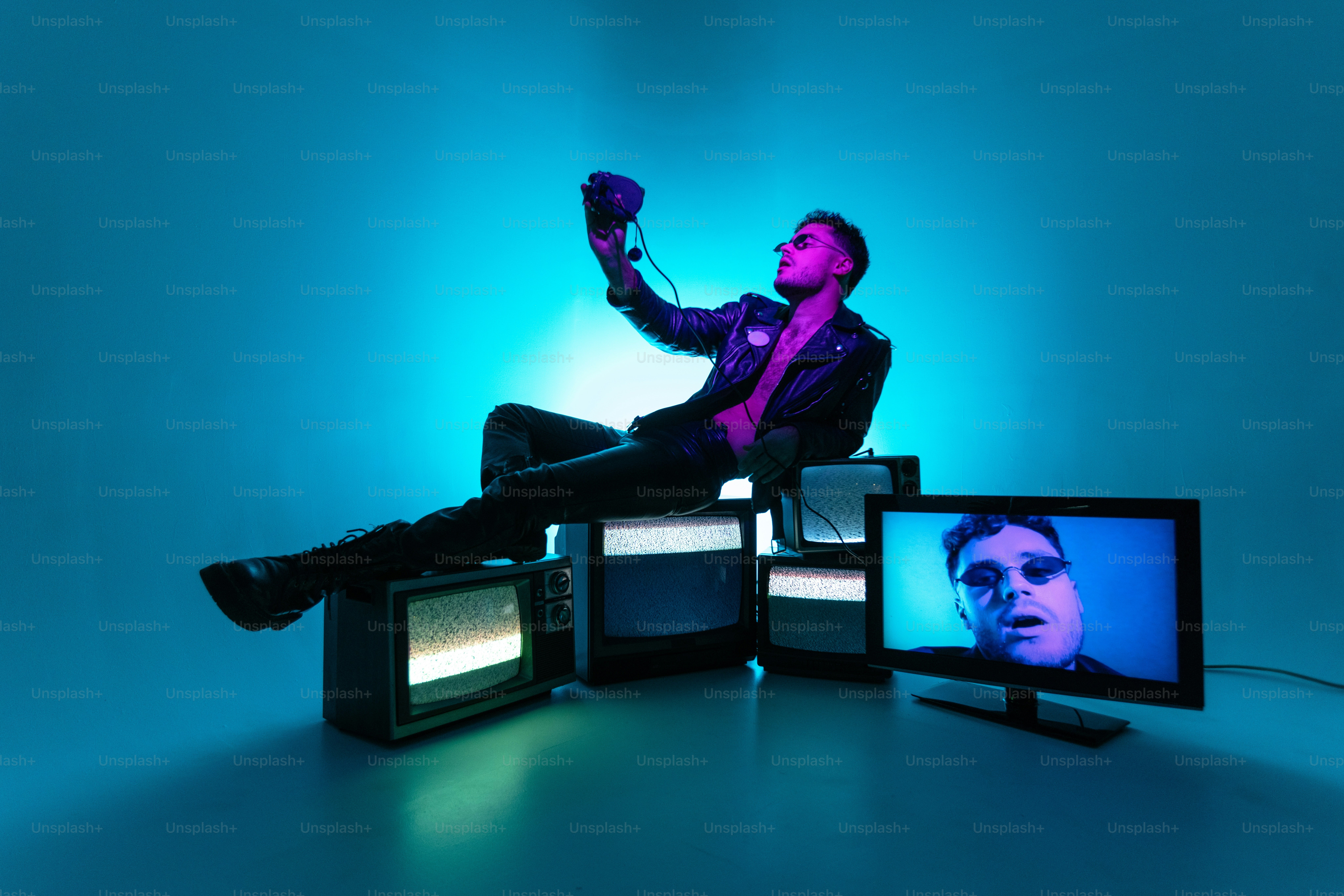 A man sitting in a chair surrounded by televisions