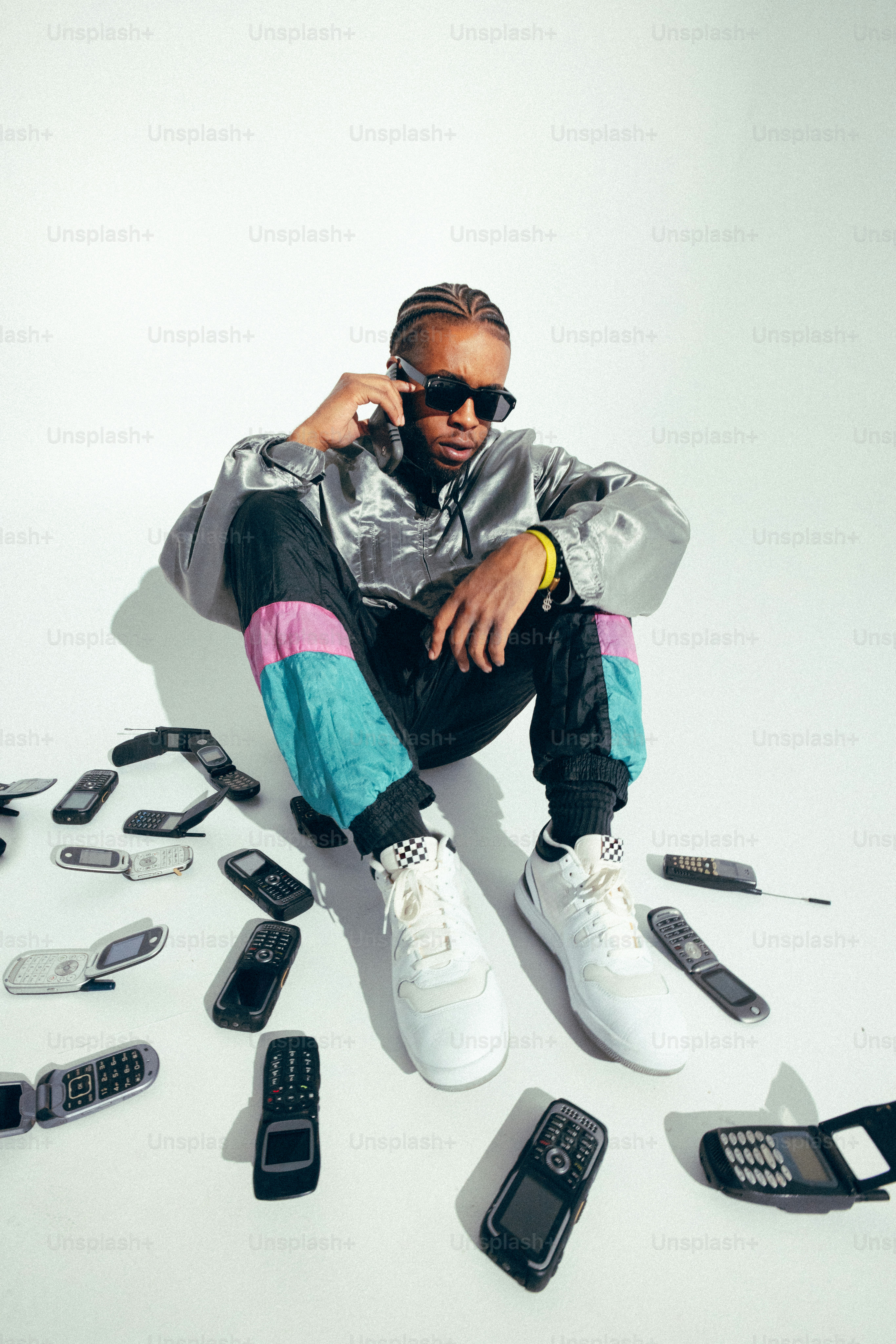 A man sitting on the ground surrounded by cell phones
