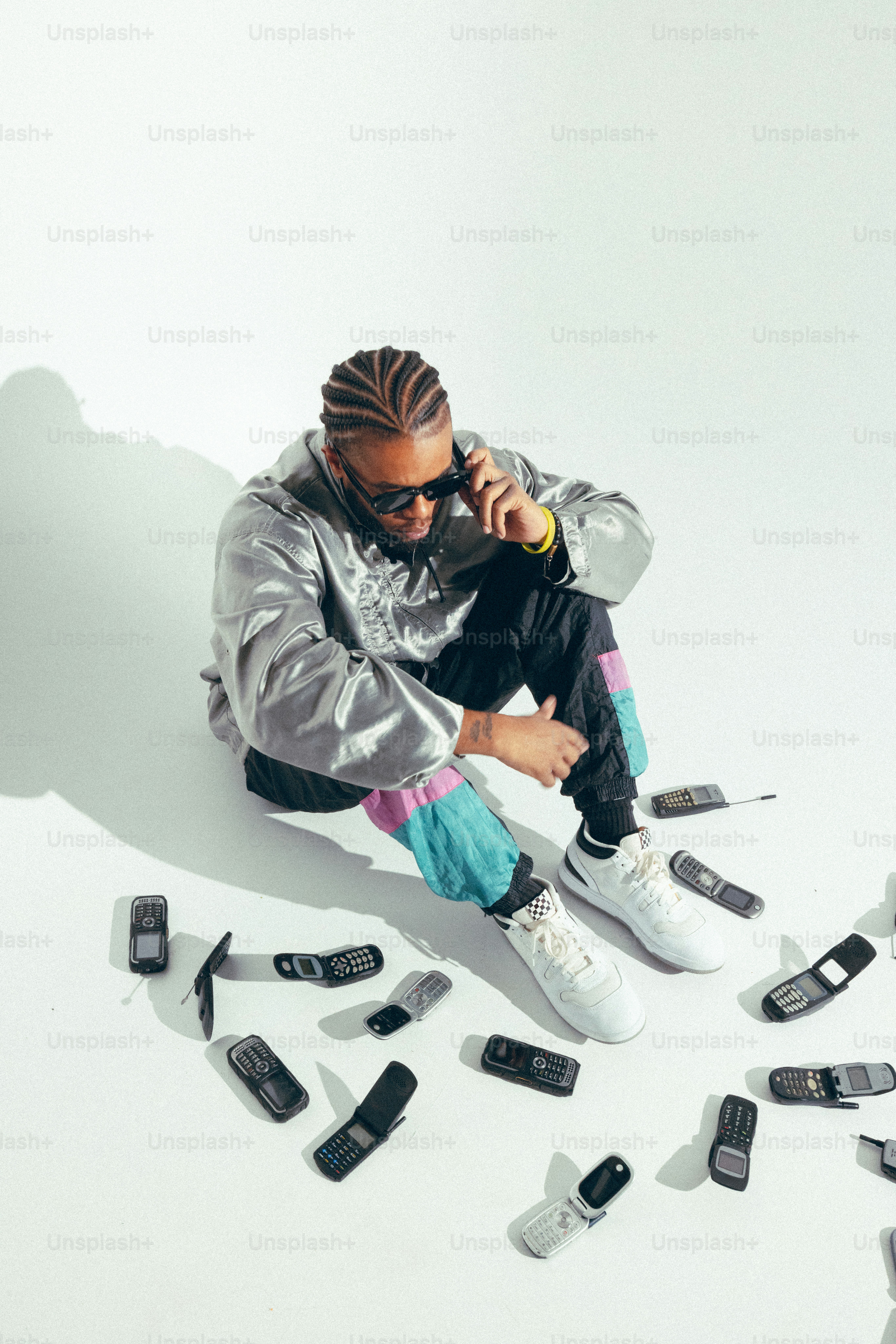 A man sitting on the ground surrounded by cell phones