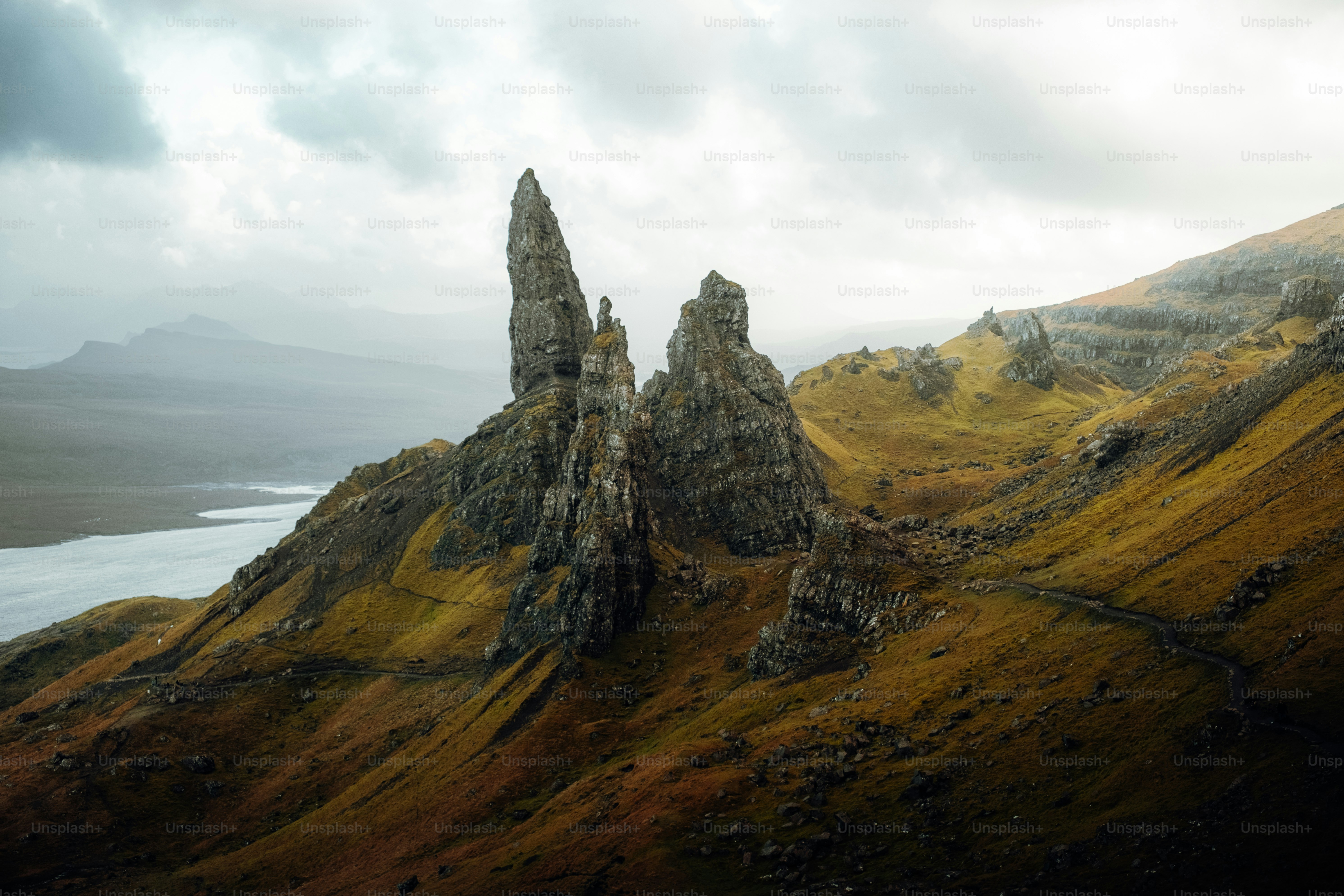 A rocky mountain with a body of water in the distance