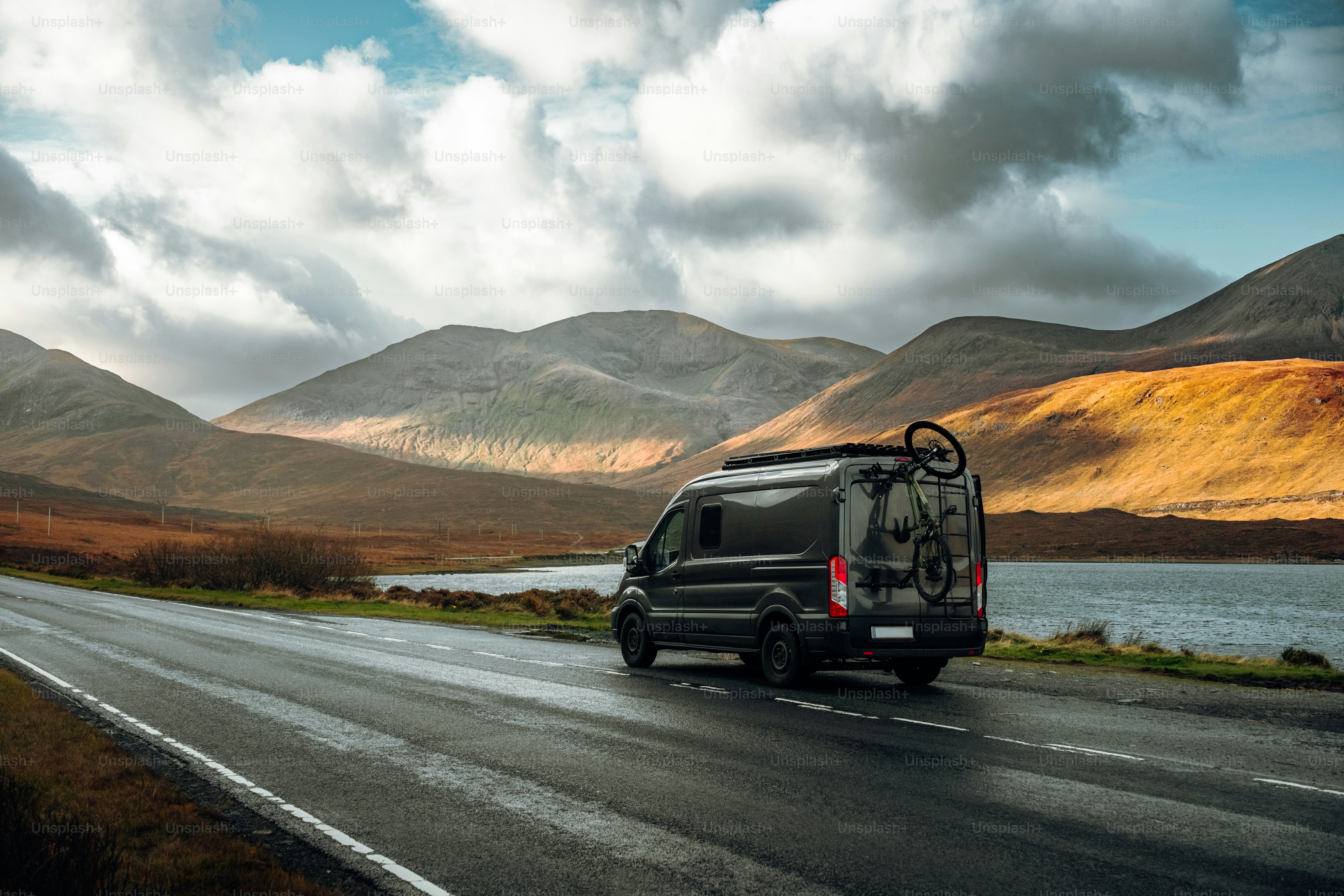 A van driving down a road with mountains in the background photo – Isle ...