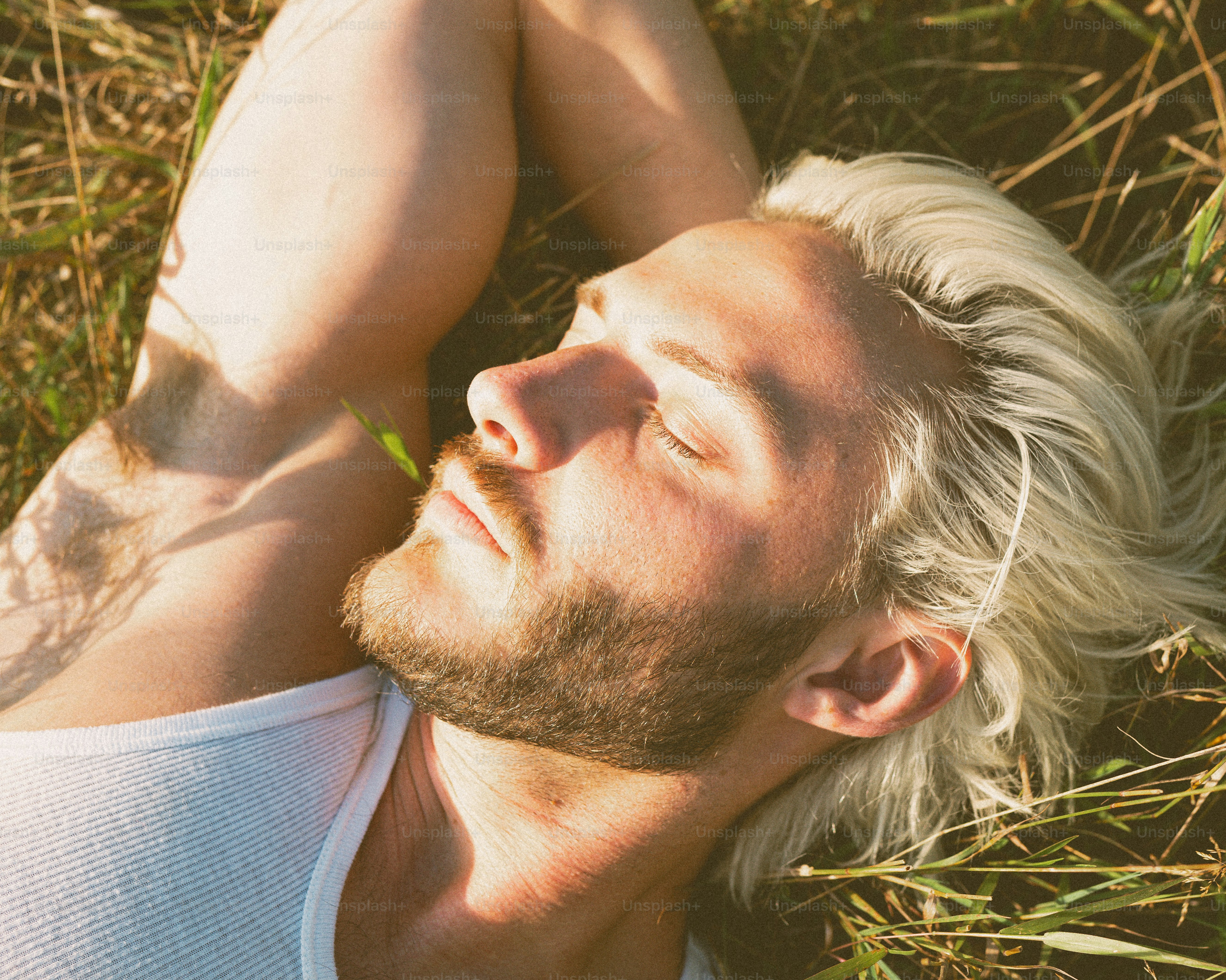 A man laying in the grass with his eyes closed