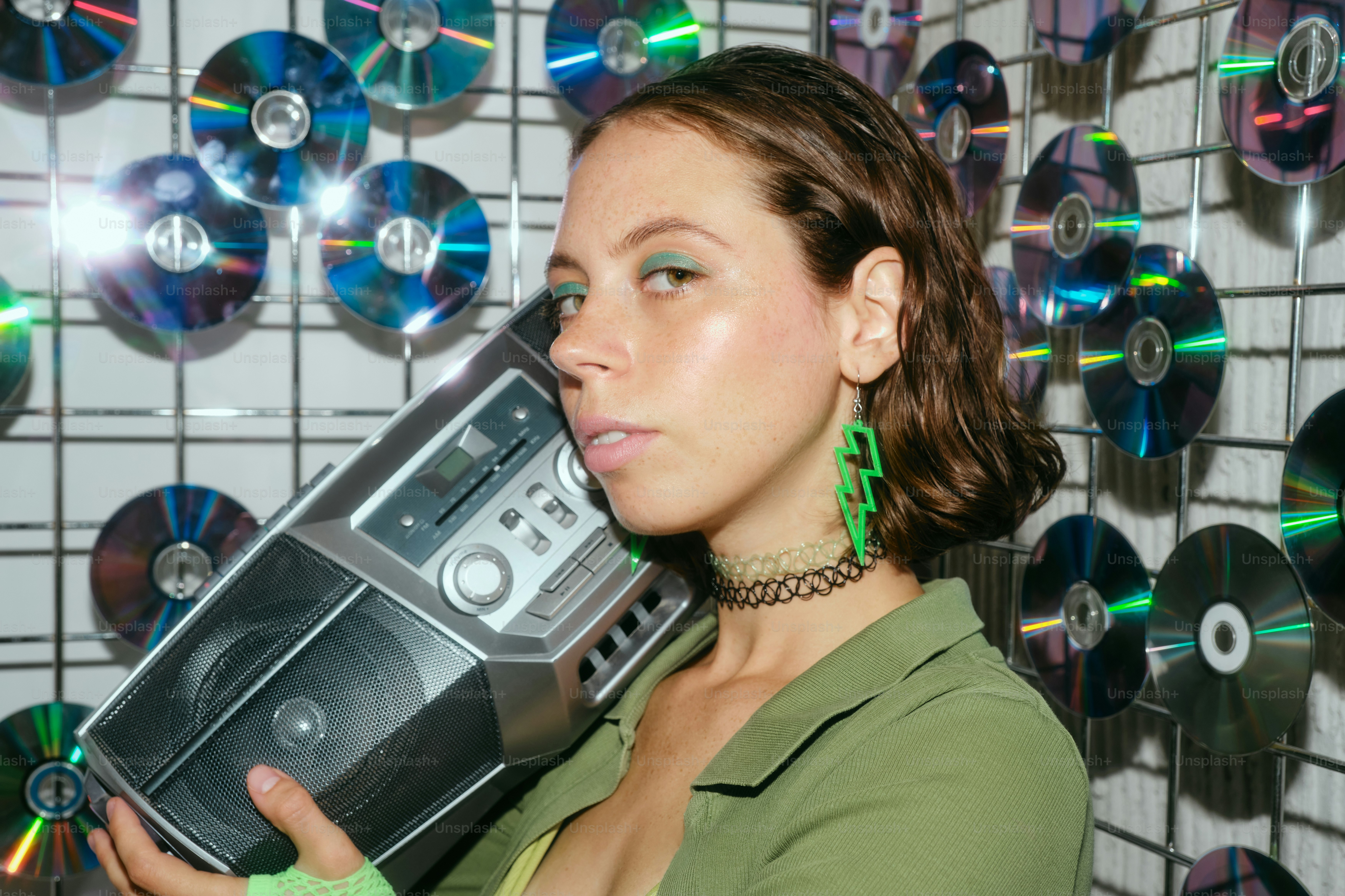 A woman holding a radio in front of a wall of cds
