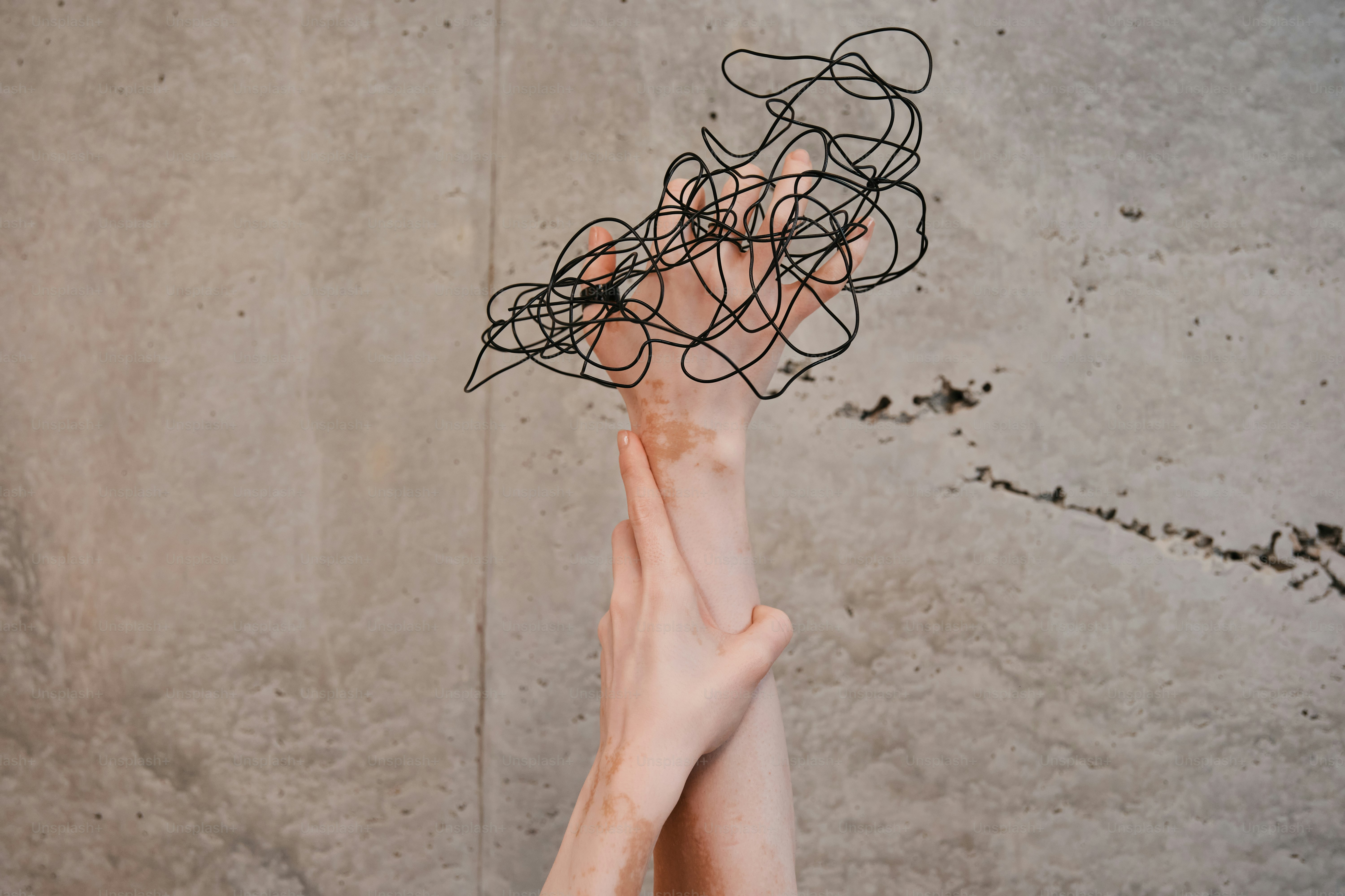 Two hands reaching up towards a wall