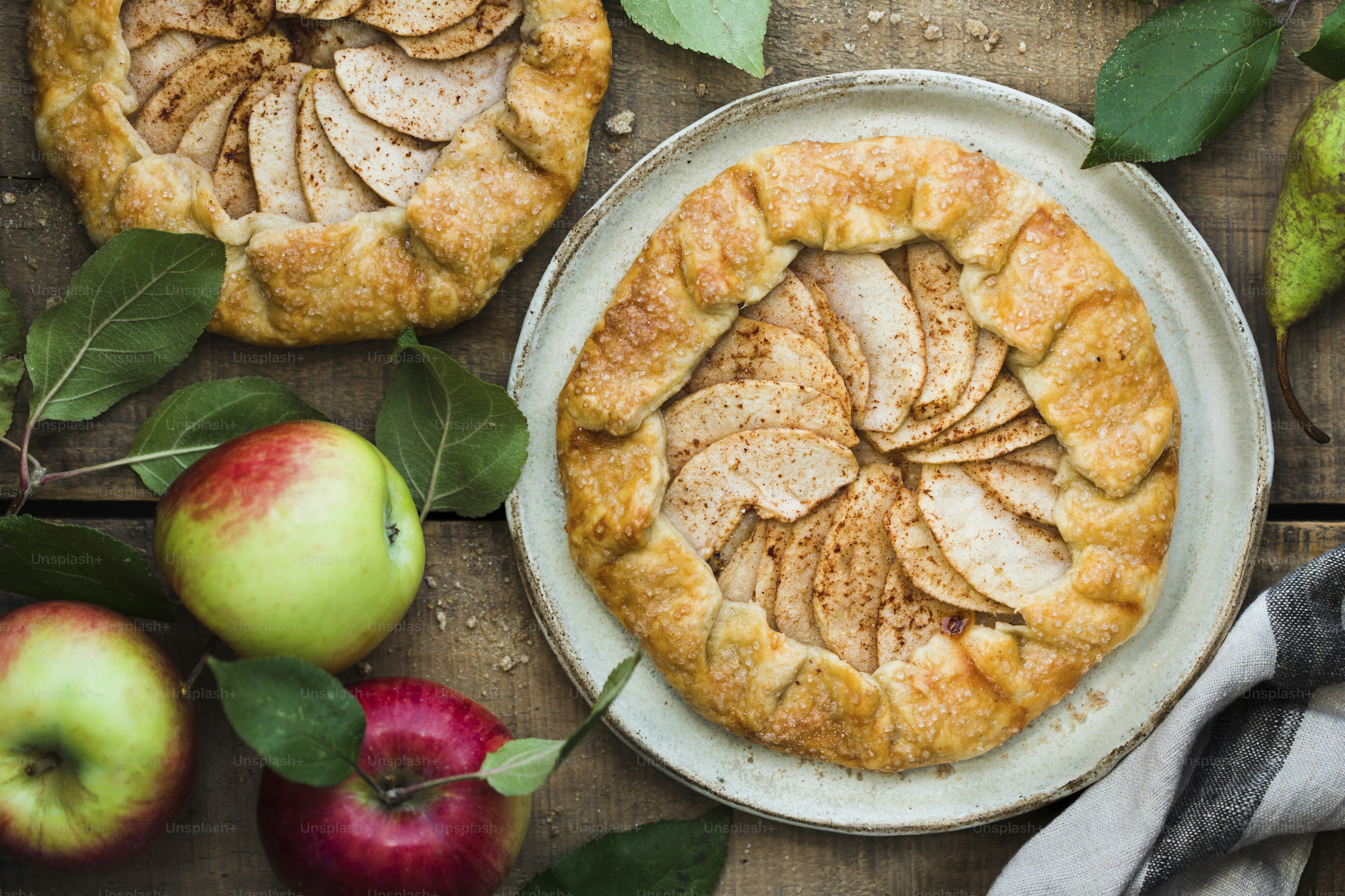 A table topped with apples and pies on top of a wooden table