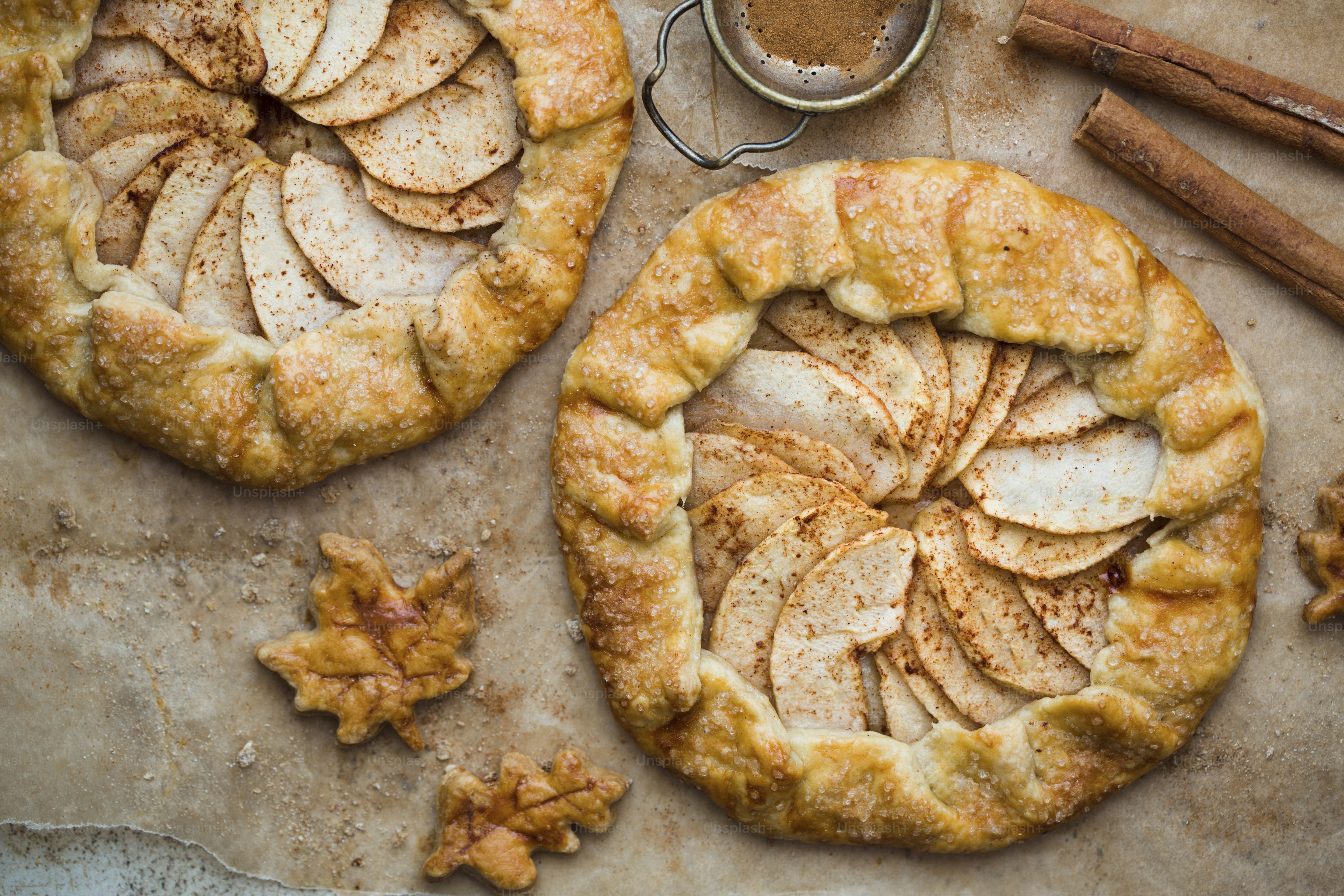 Two apple pies on a table with cinnamon sticks