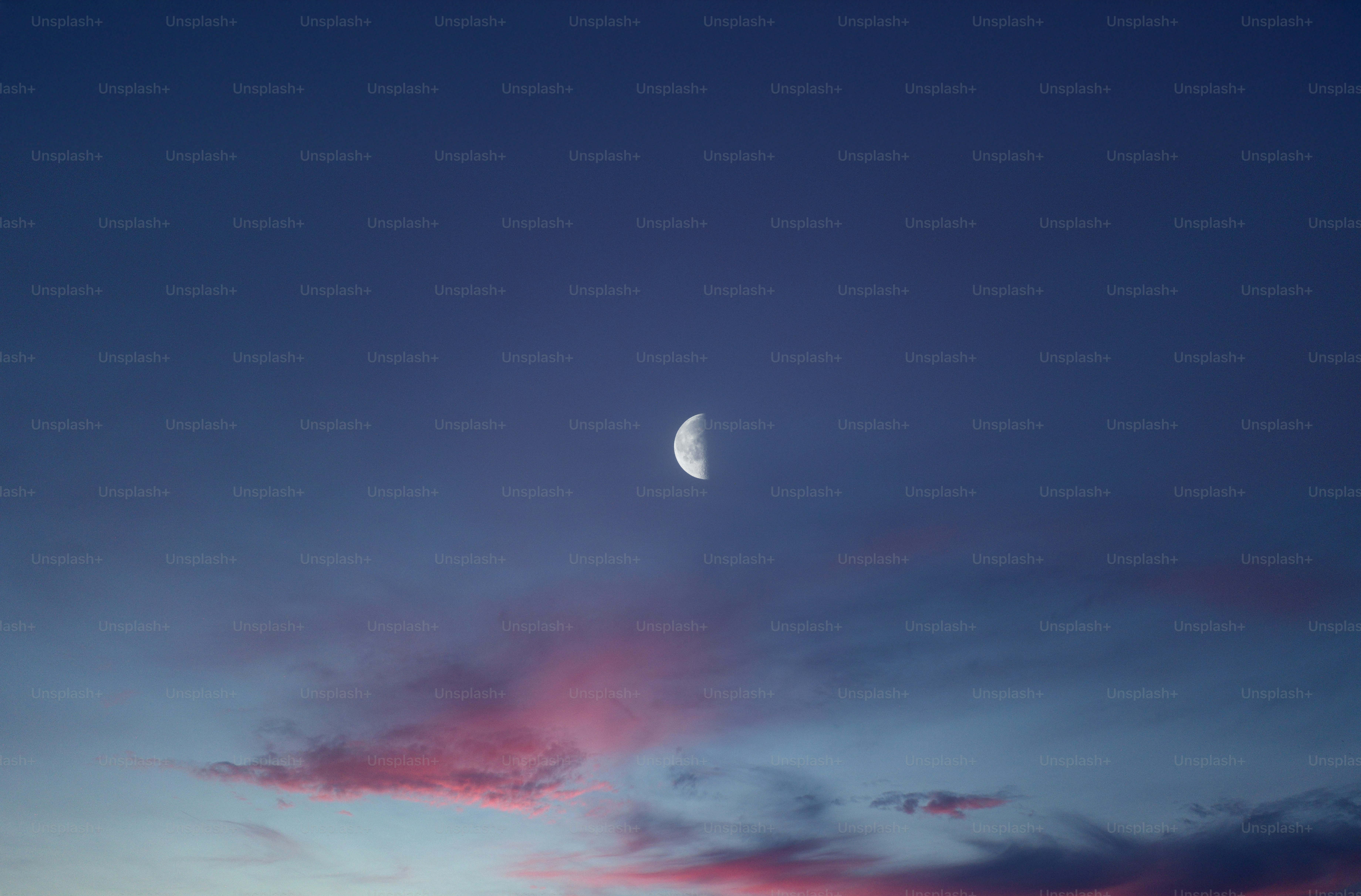 The moon is setting in the sky above the clouds