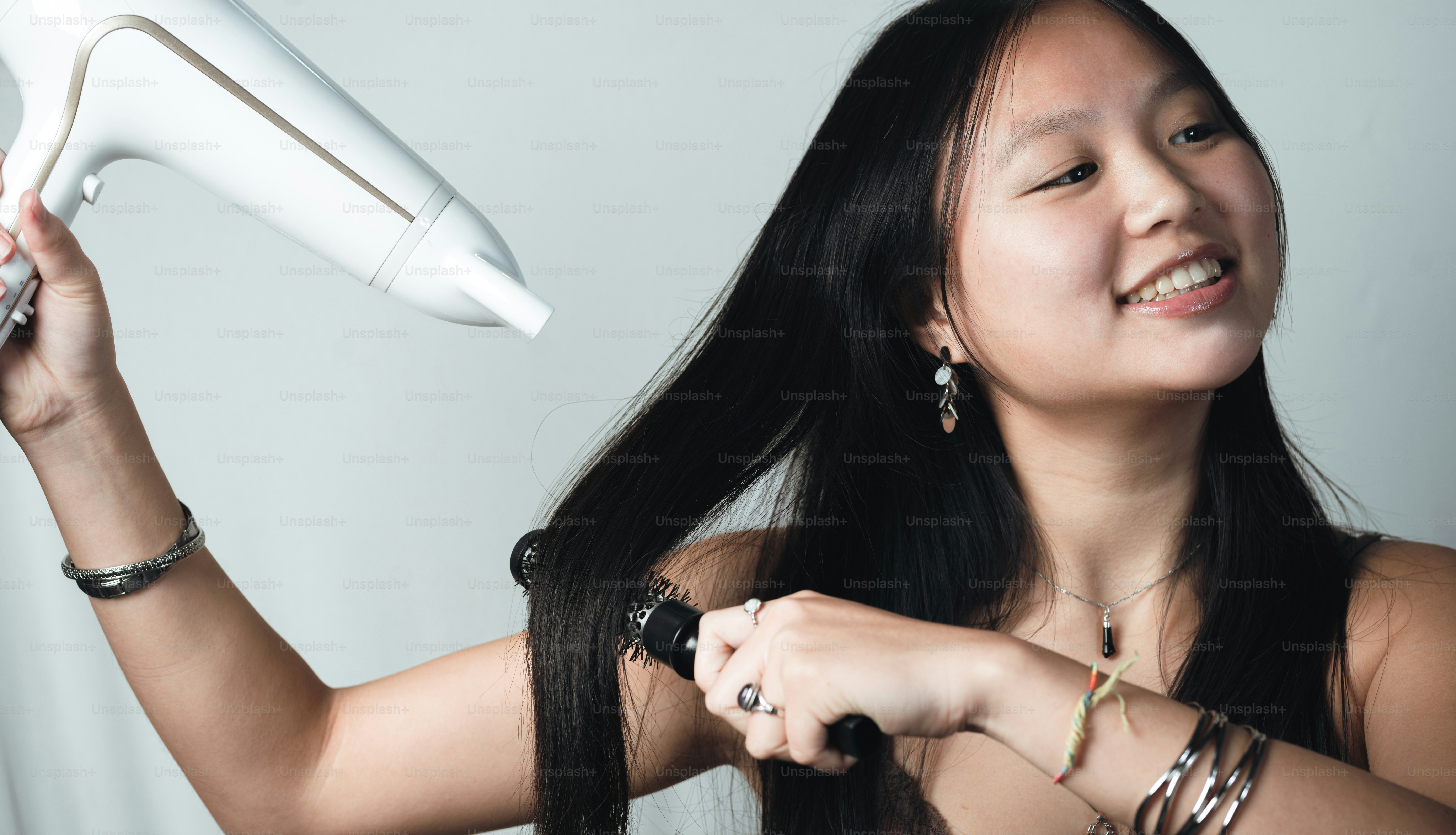 A woman blow drying her hair with a hair dryer