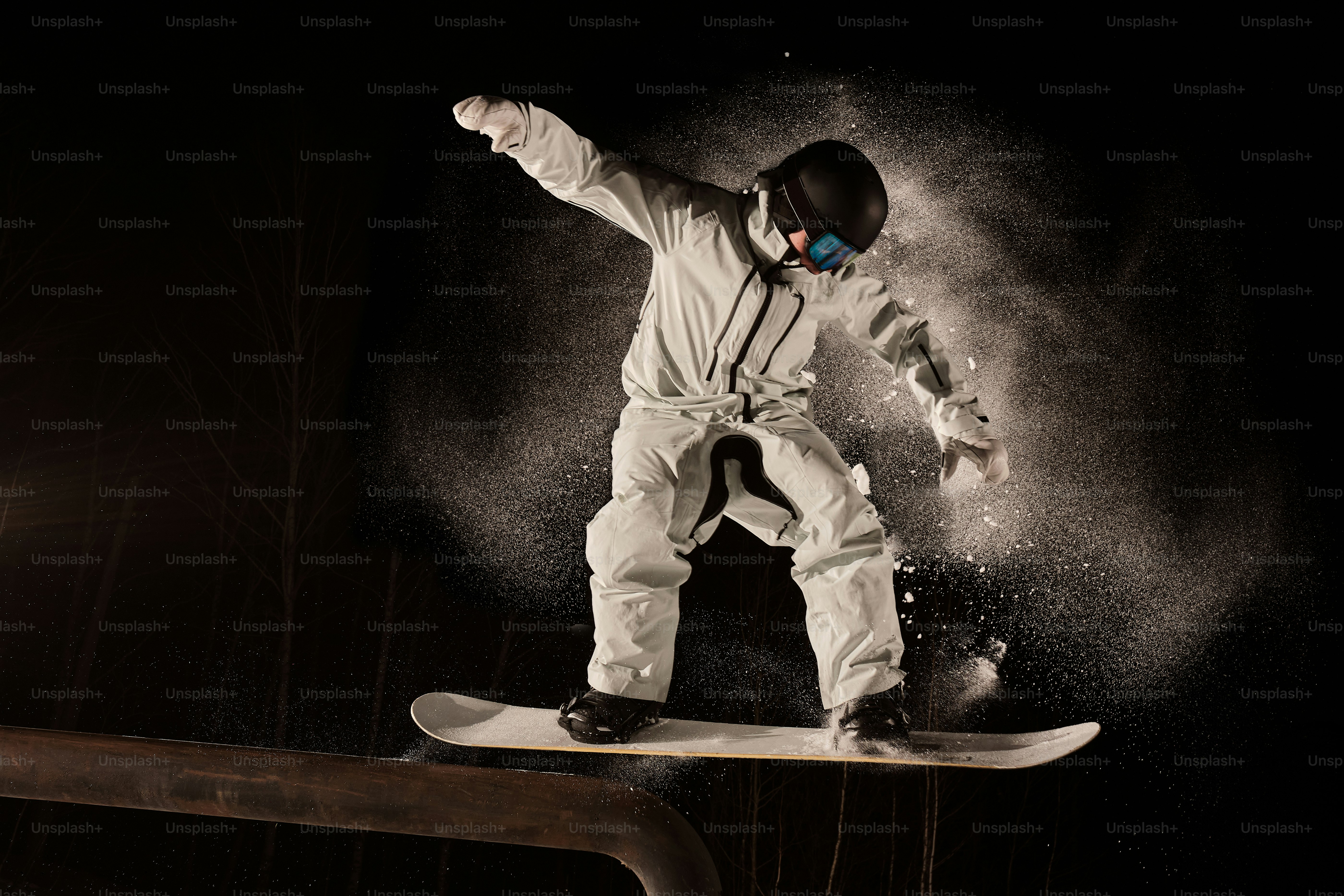A man riding a snowboard on top of a wooden rail photo – Night Image on ...