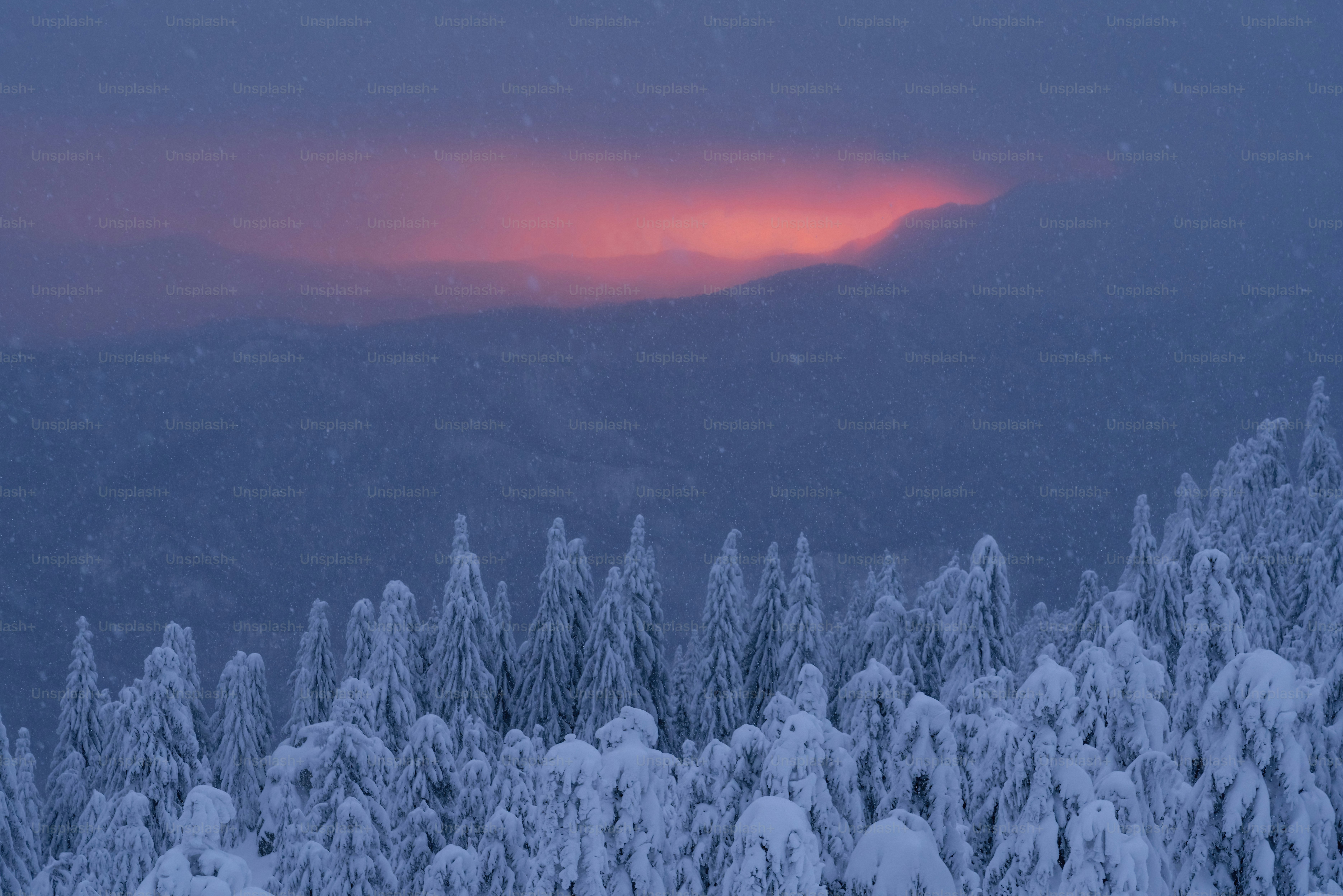 The sun is setting over the snowy mountains