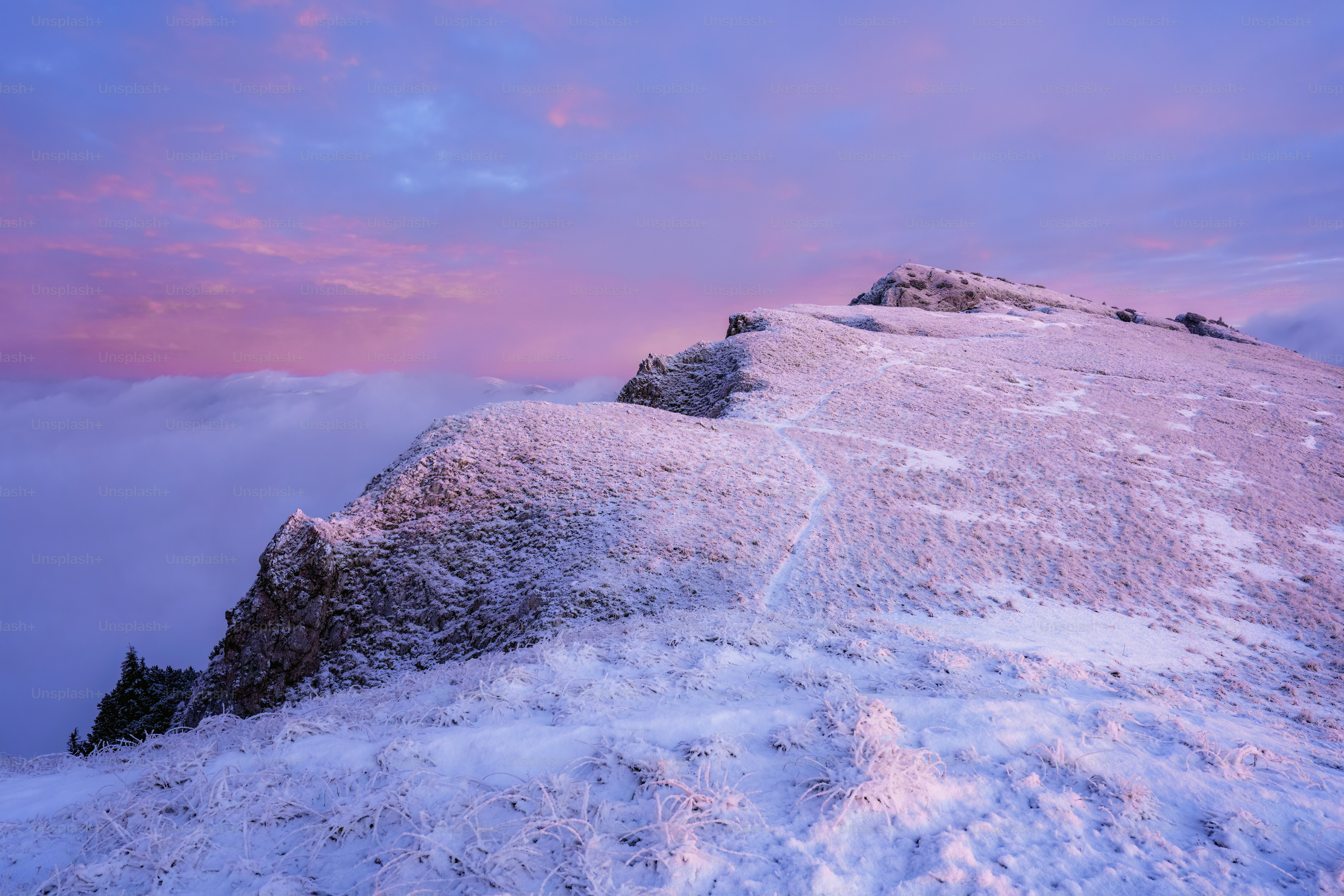 A mountain covered in snow under a pink sky