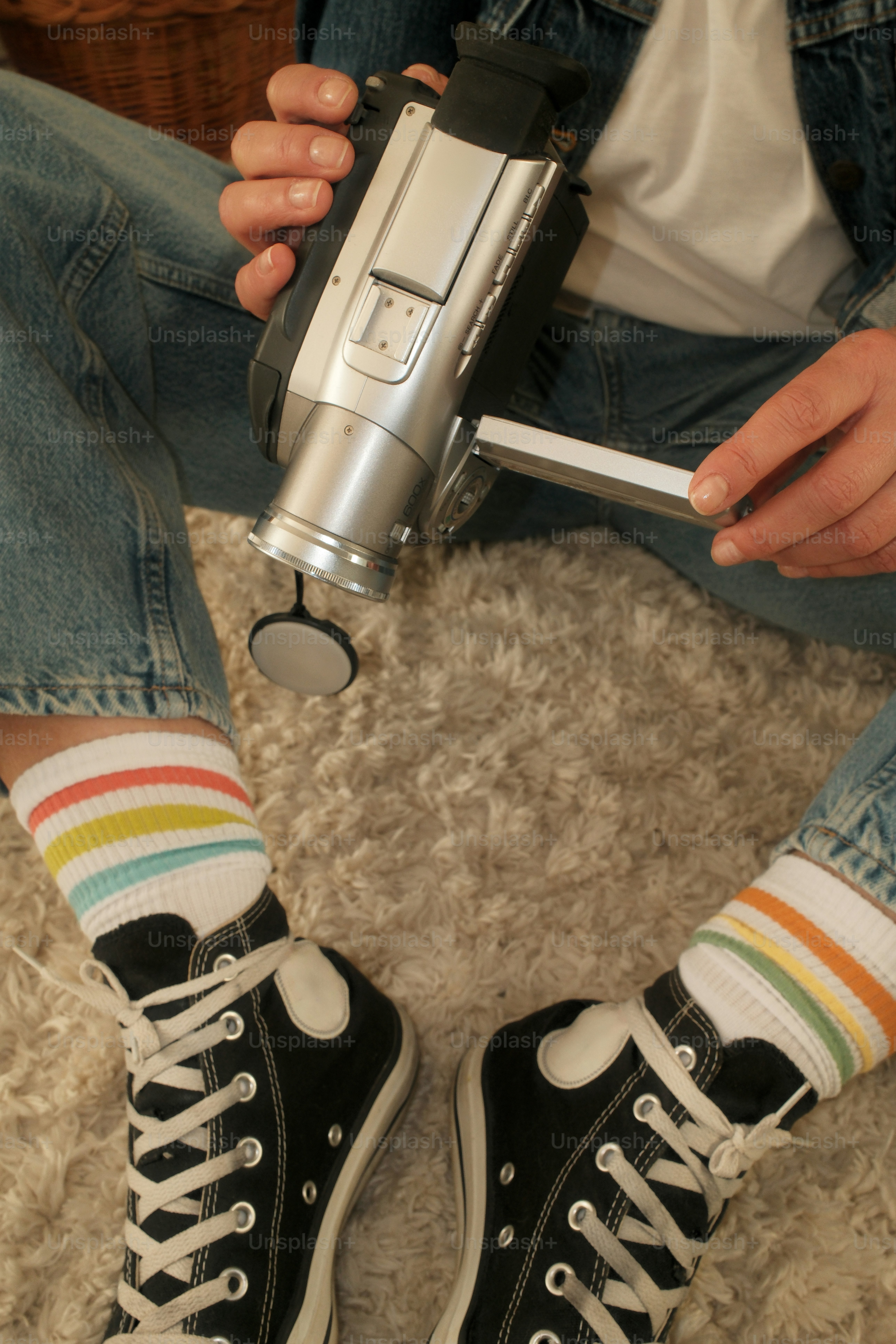 Una persona sentada en el suelo sosteniendo una cámara