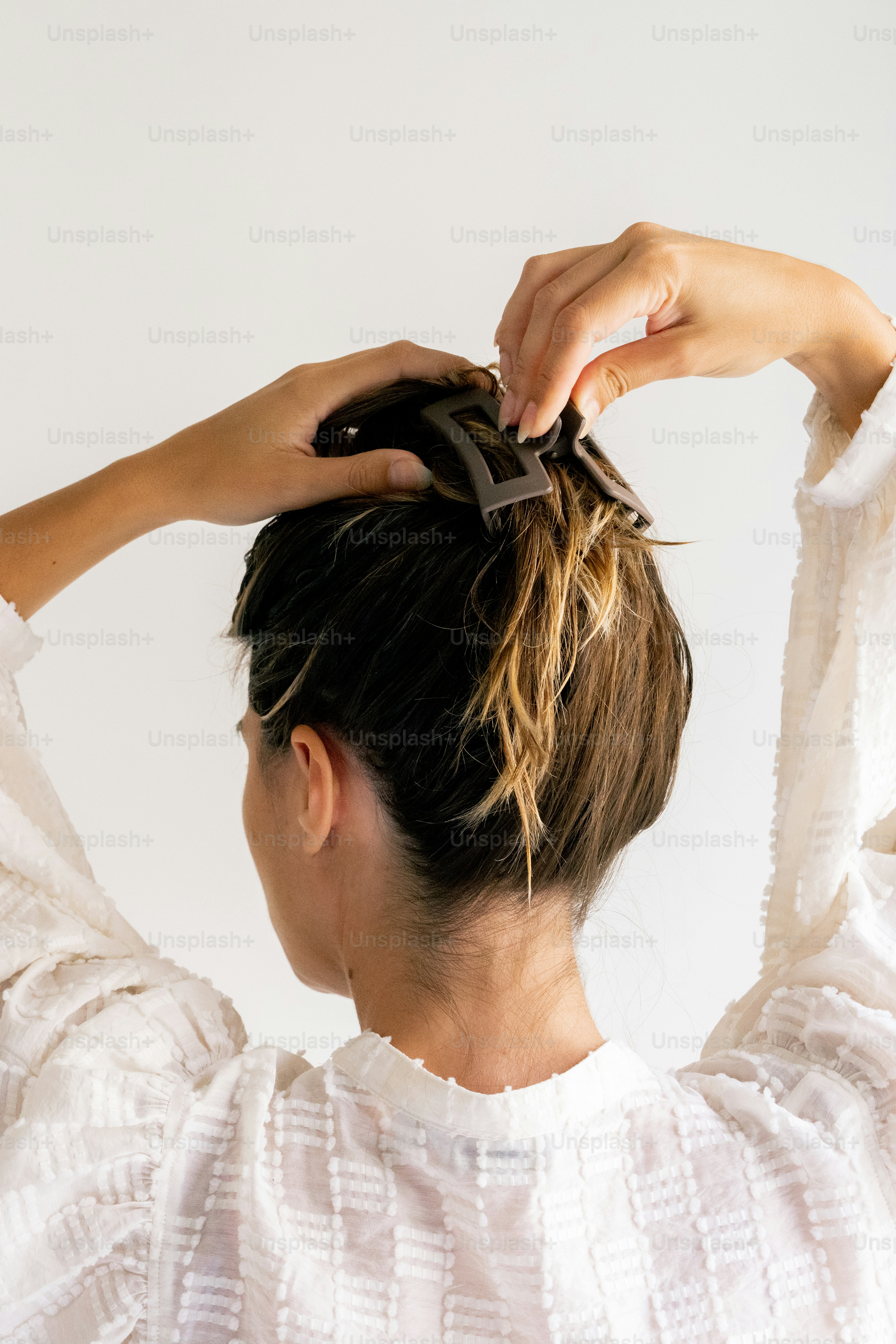 A woman in a white top is tying her hair