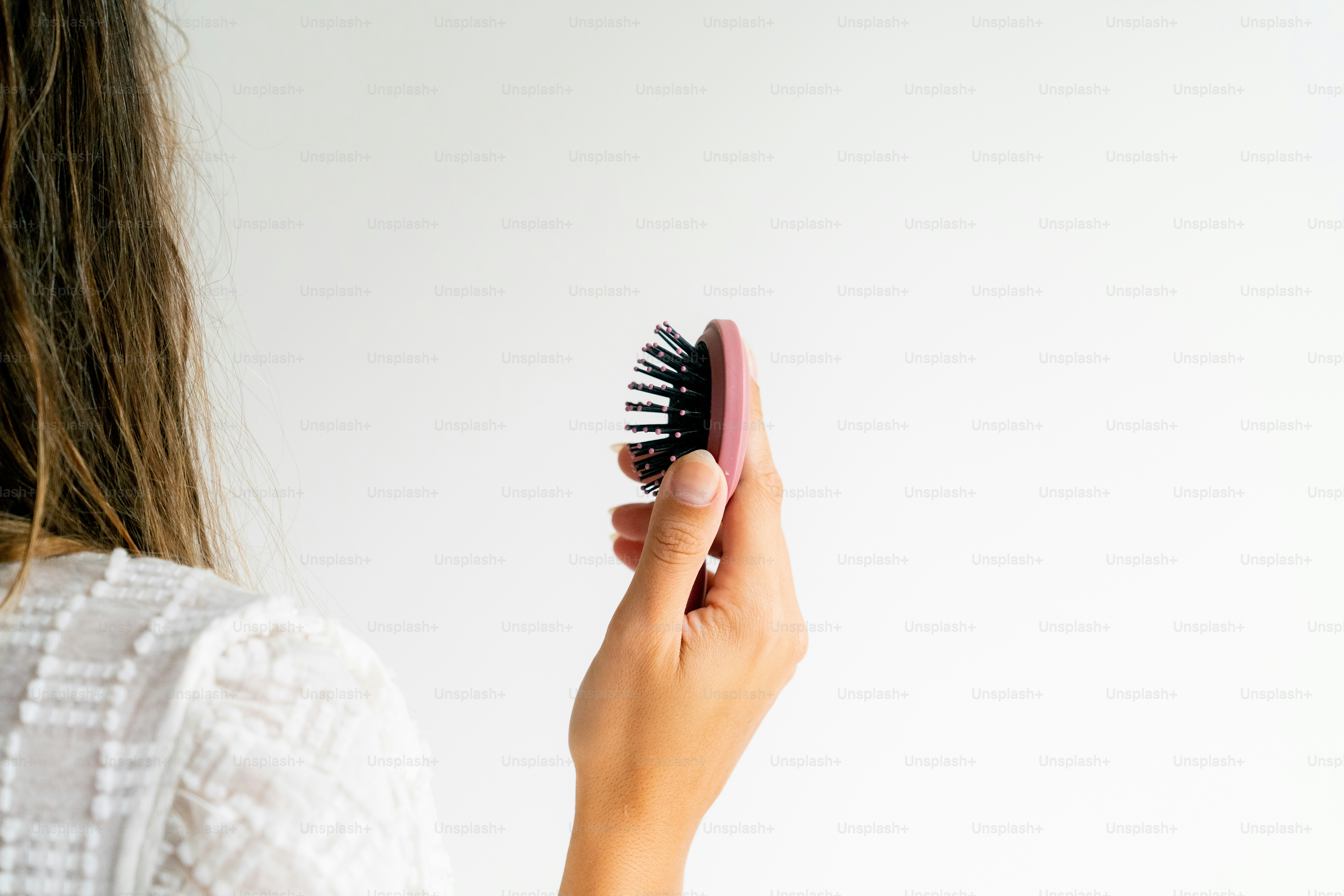 A woman brushes her hair with a brush