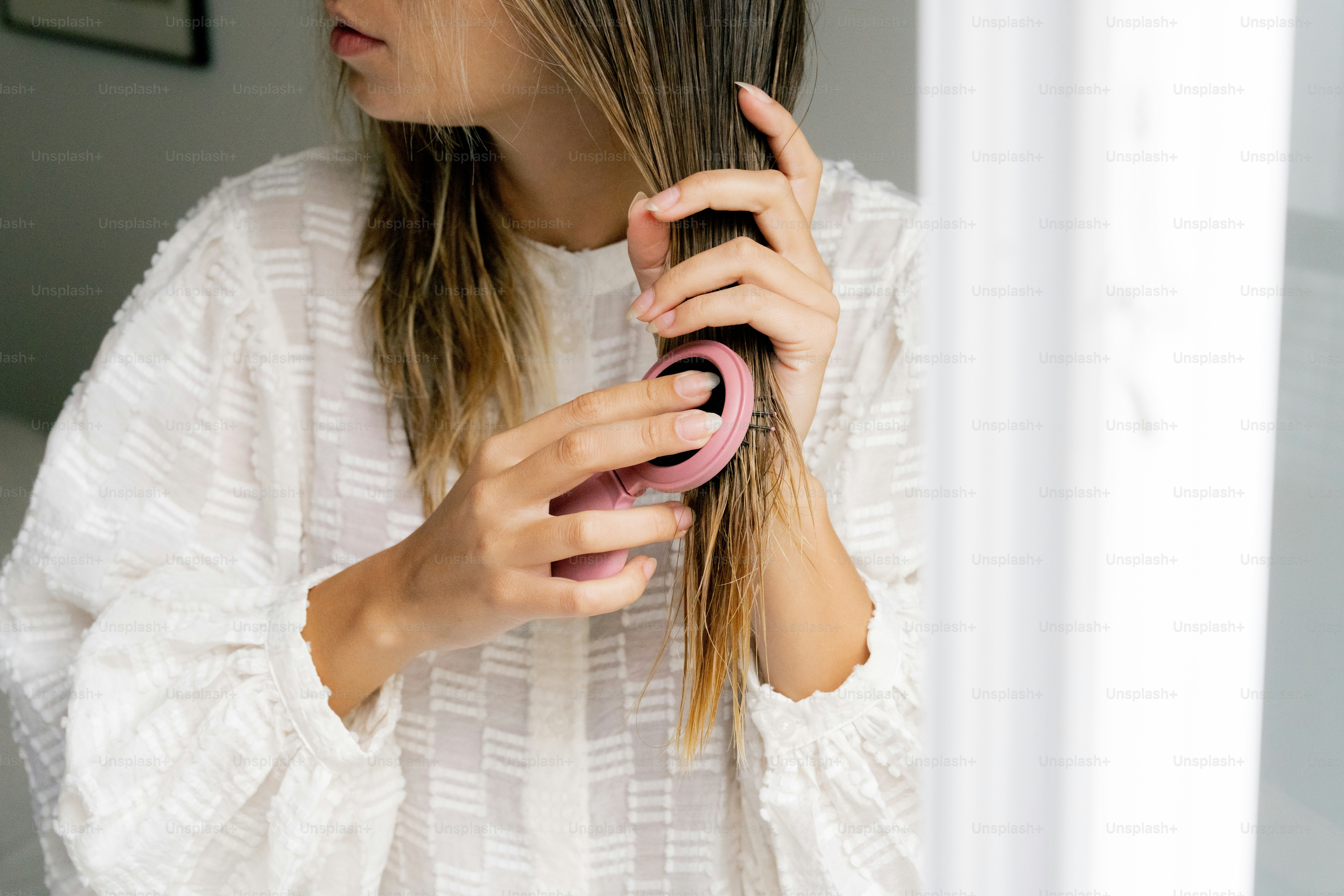 A woman is blow drying her hair in the bathroom
