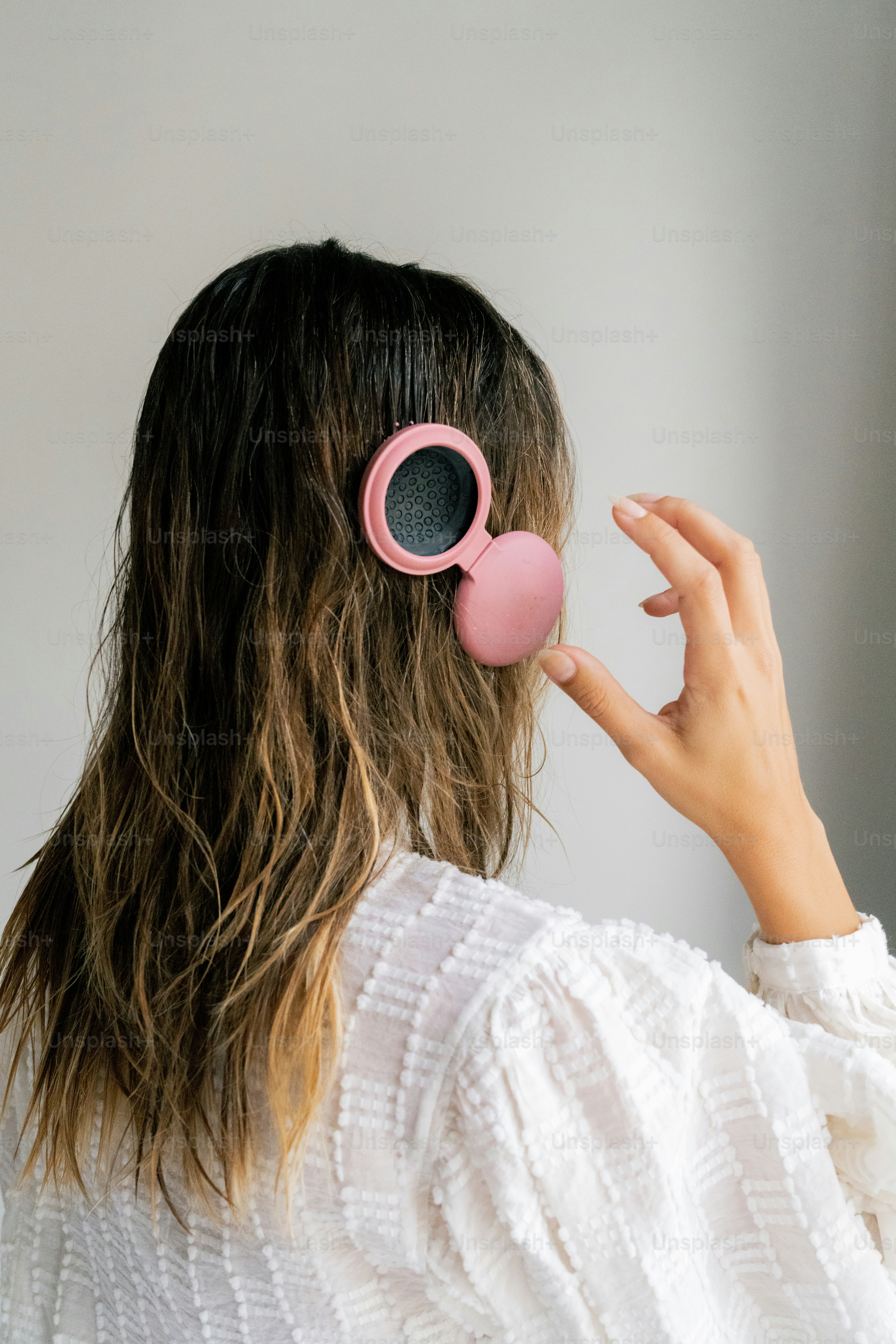 A woman with long hair wearing a pair of pink ear buds