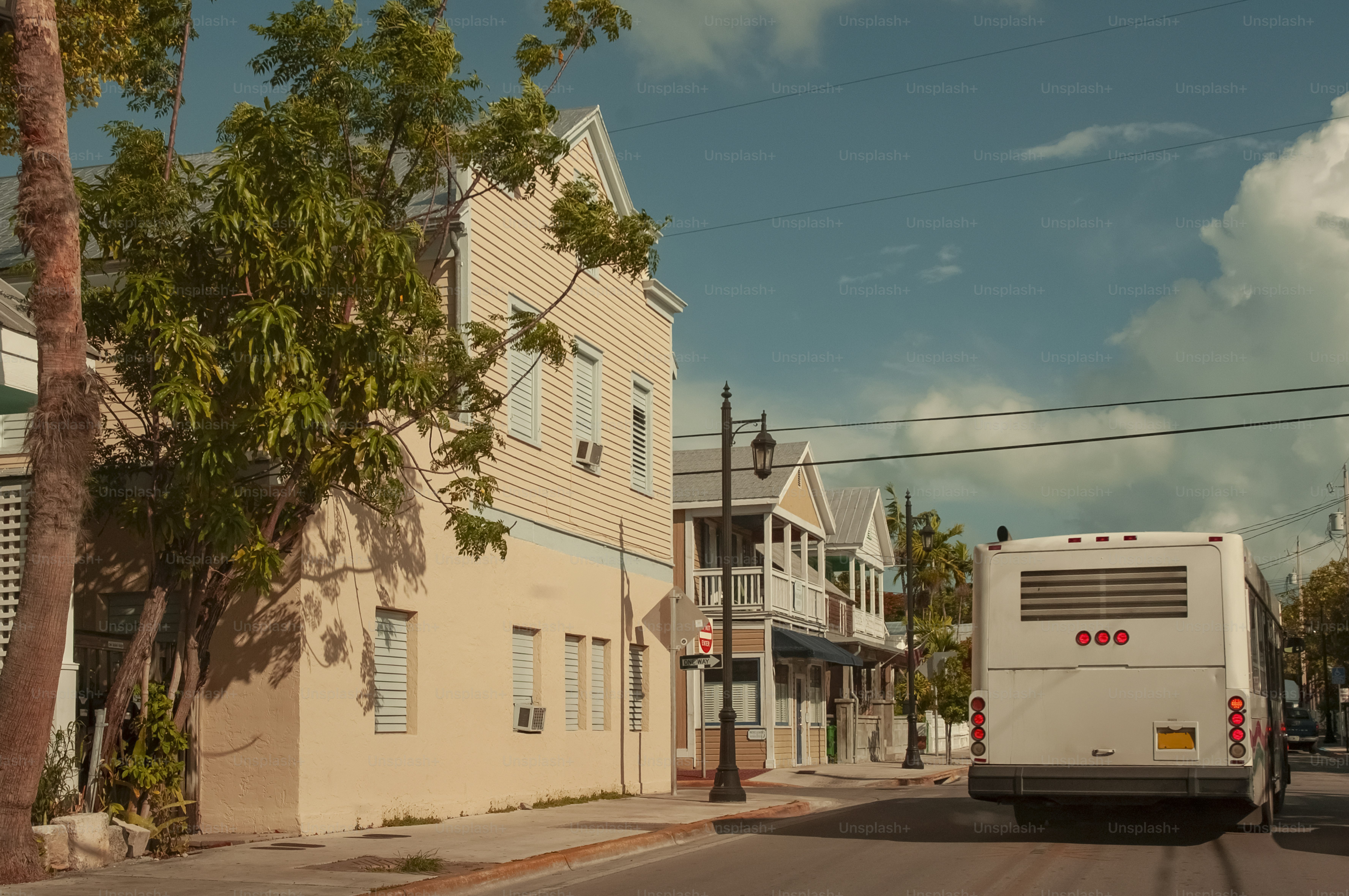 A white bus driving down a street next to tall buildings