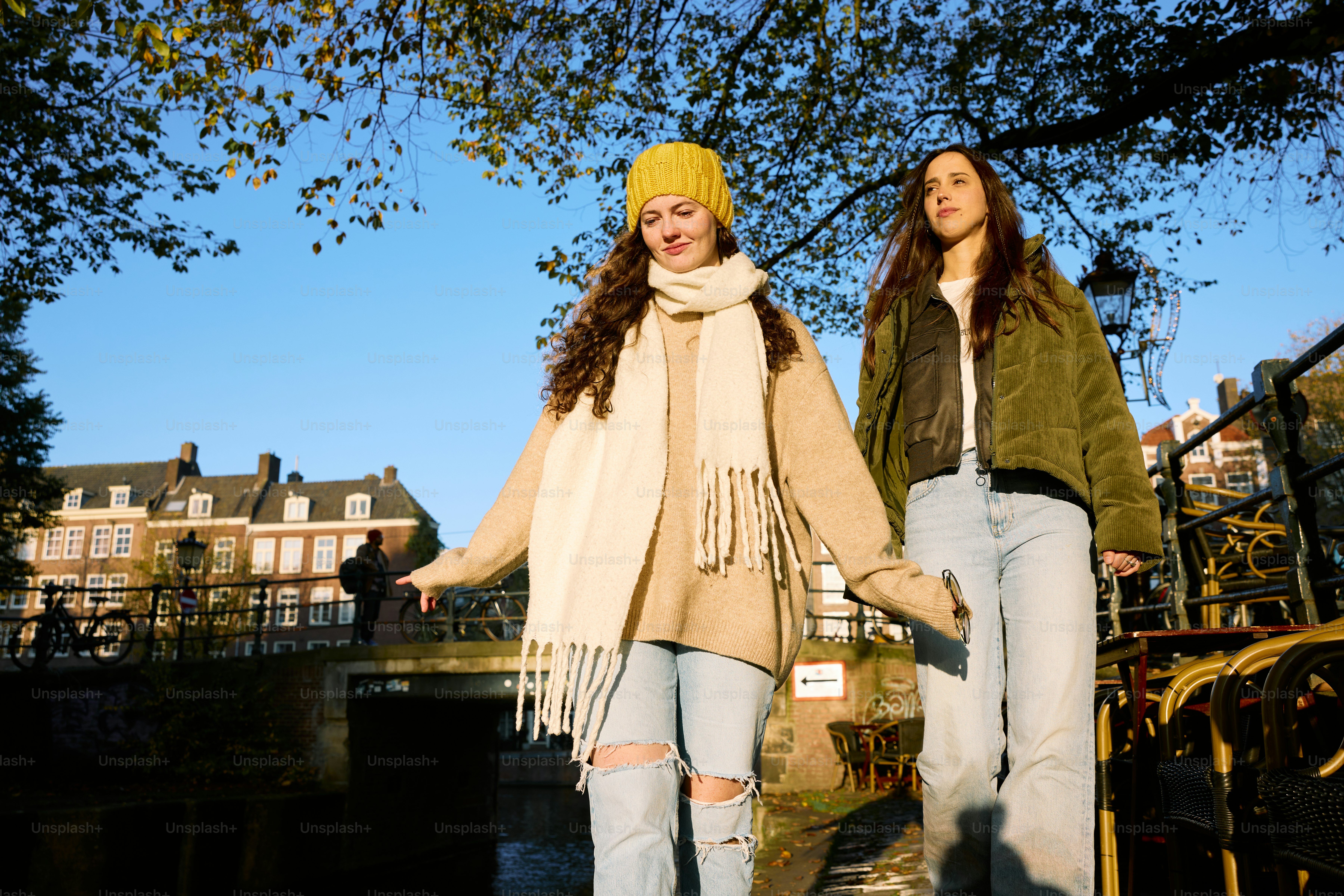 Two young women walking down a sidewalk next to a river