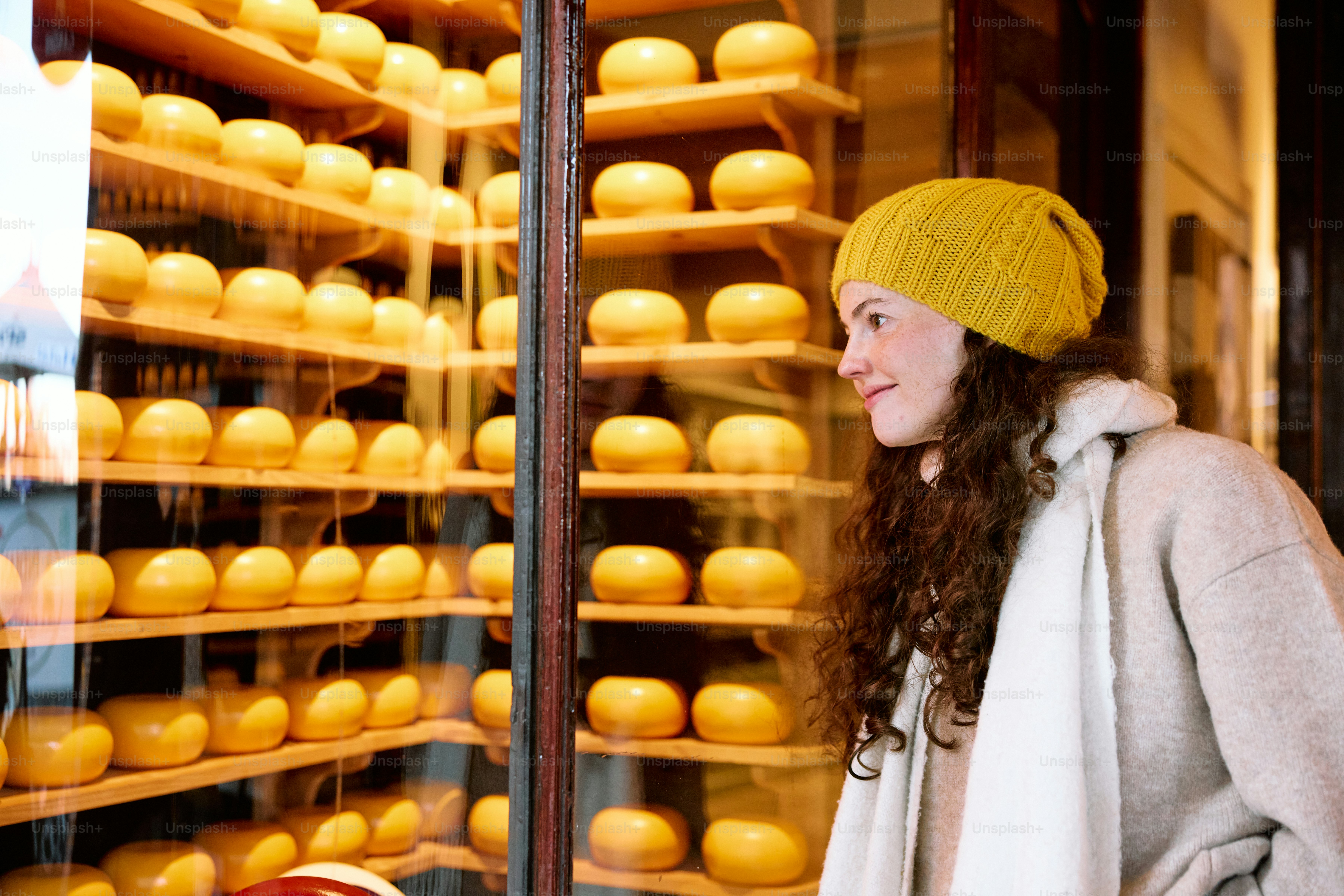A woman standing in front of a display of cheeses