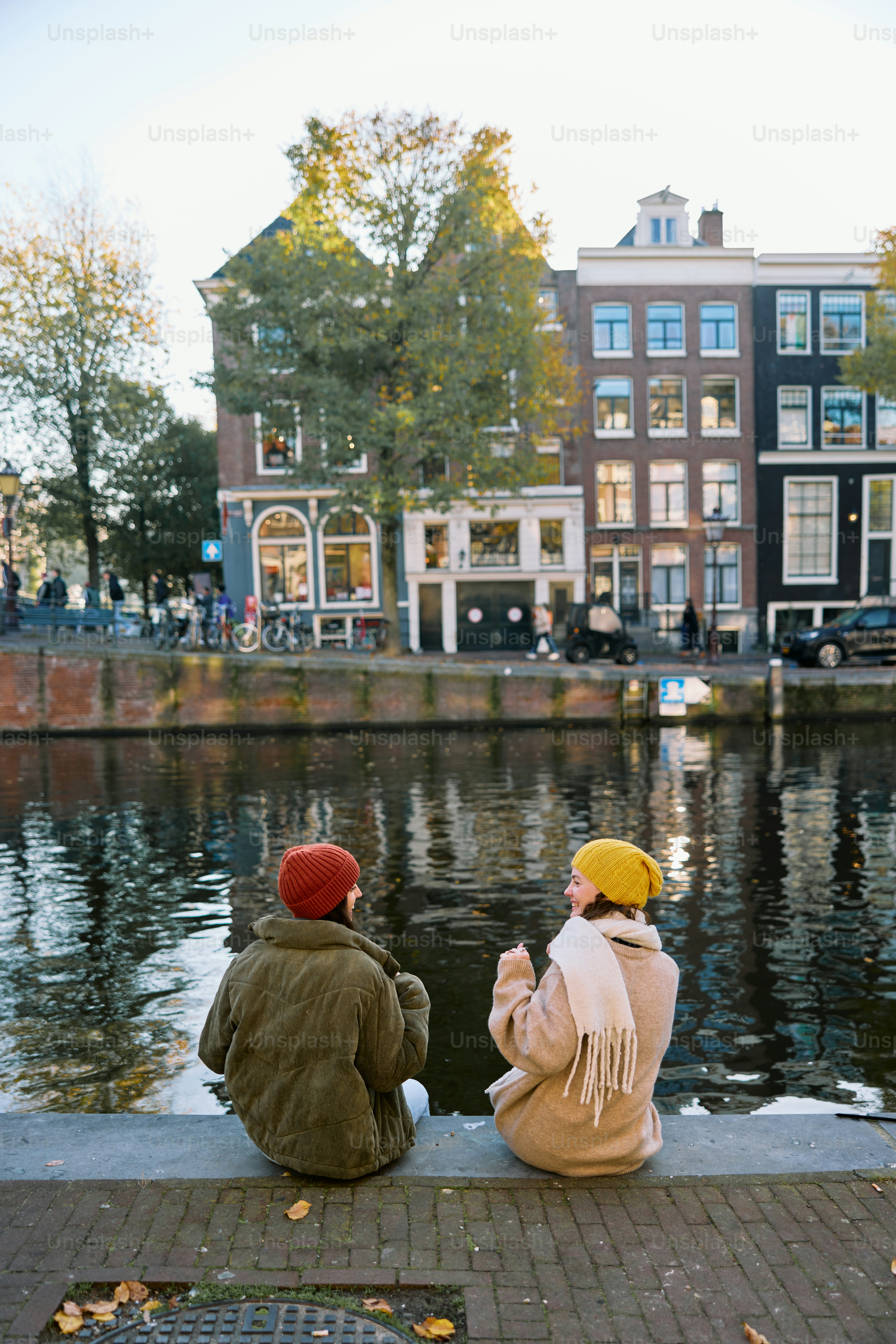 Two people sitting on the edge of a body of water