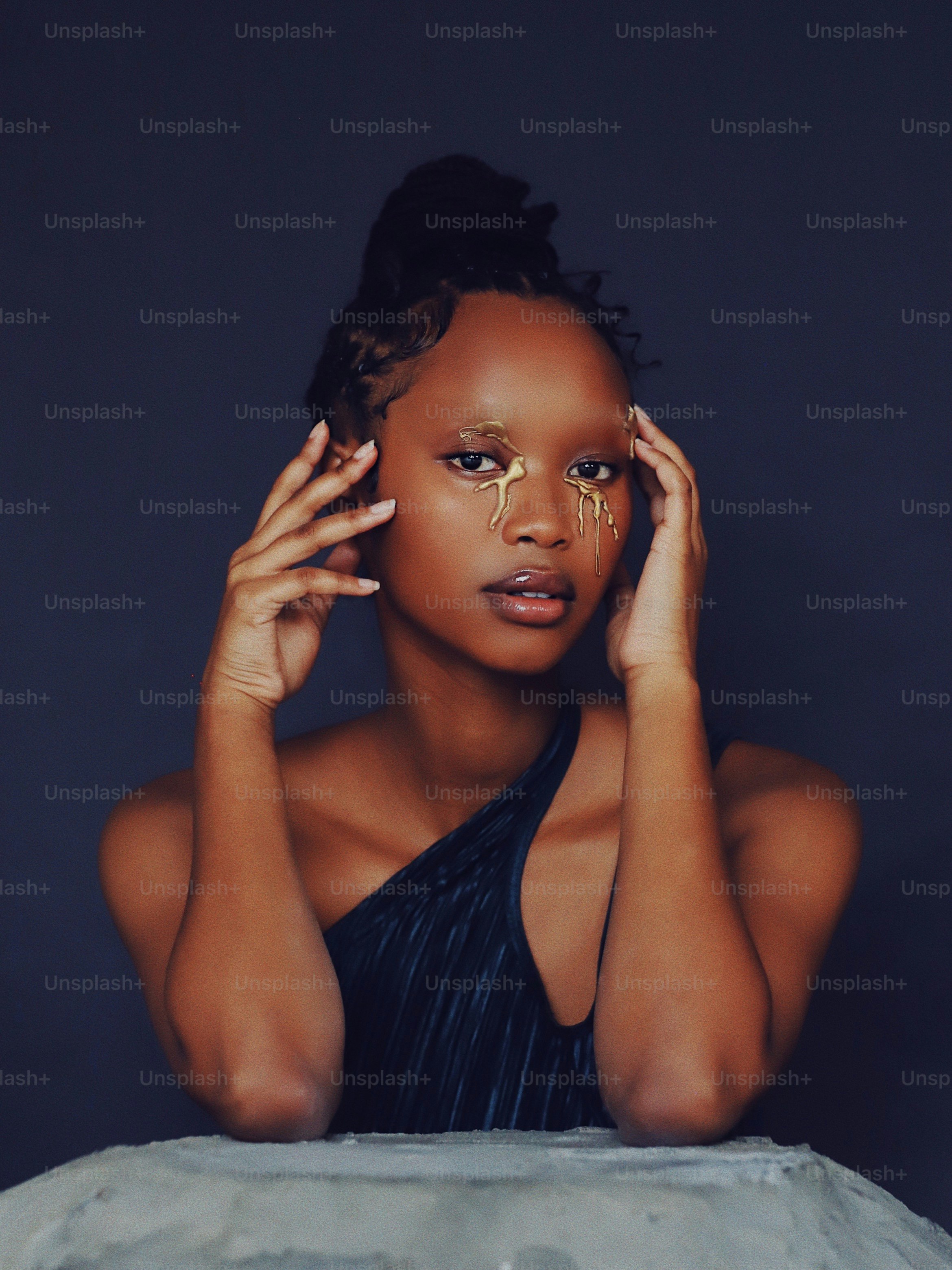 A woman with a black dress is holding her hands to her face