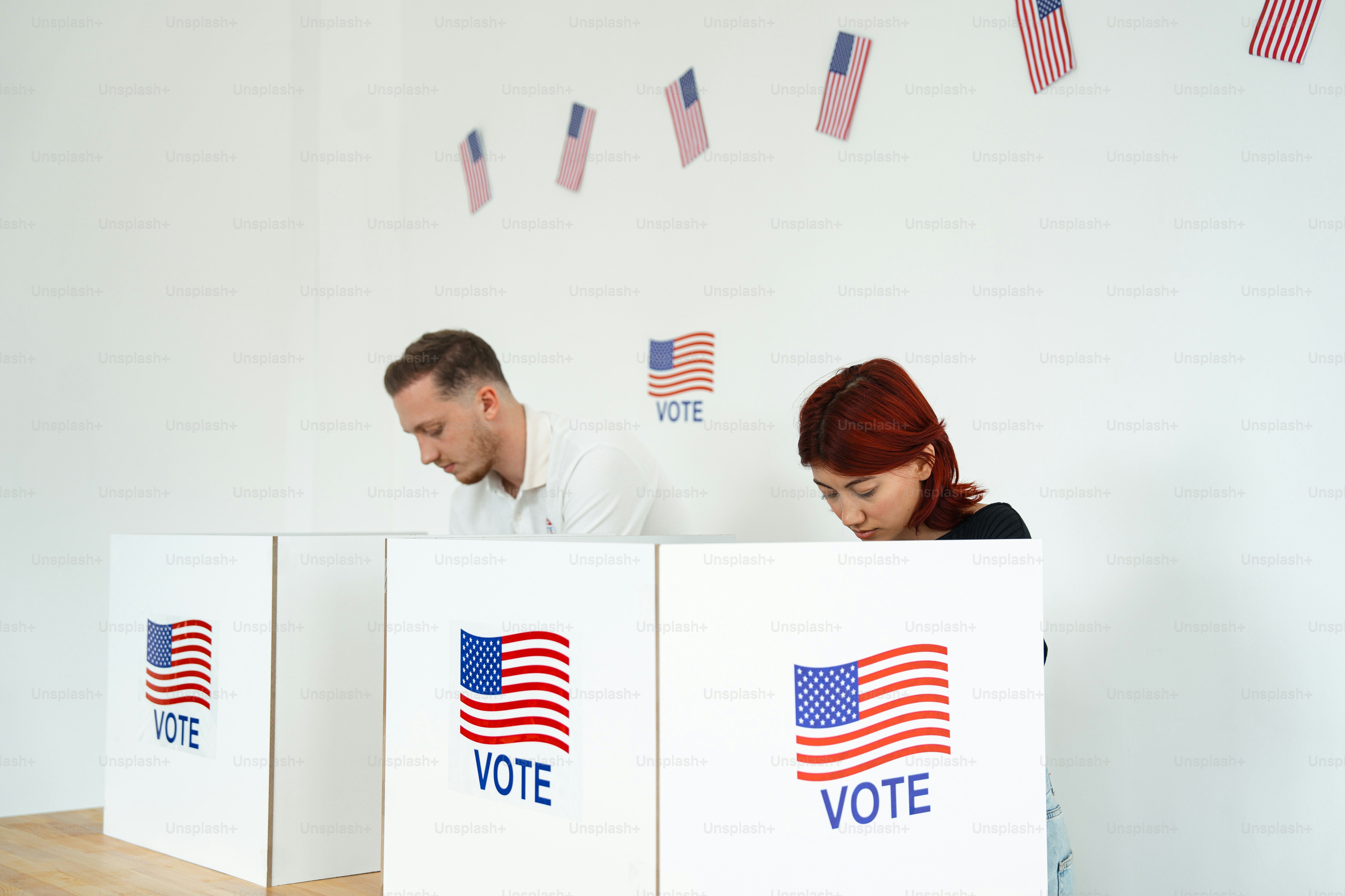 A man and a woman sitting behind voting boxes