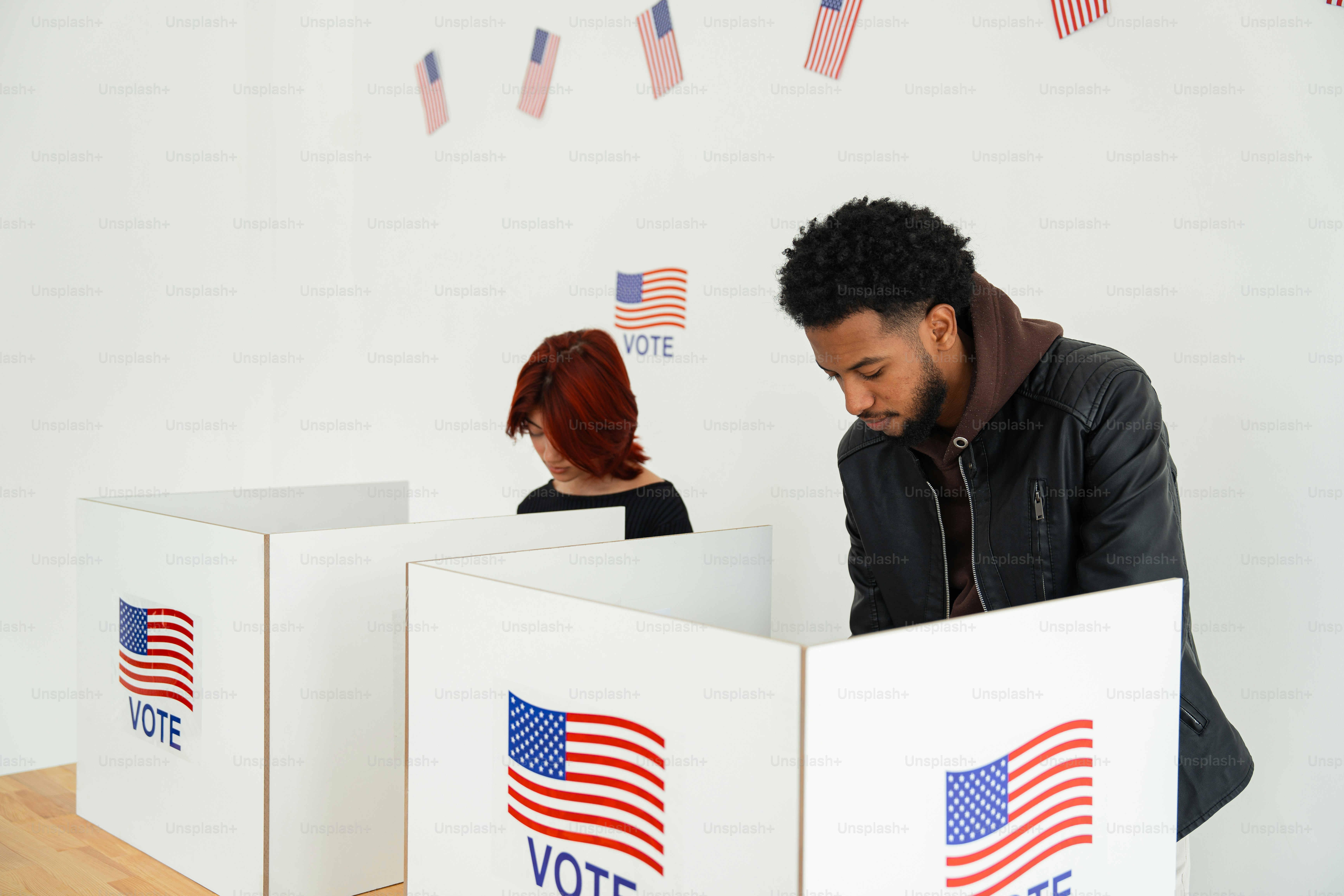 A man and a woman standing behind a voting box