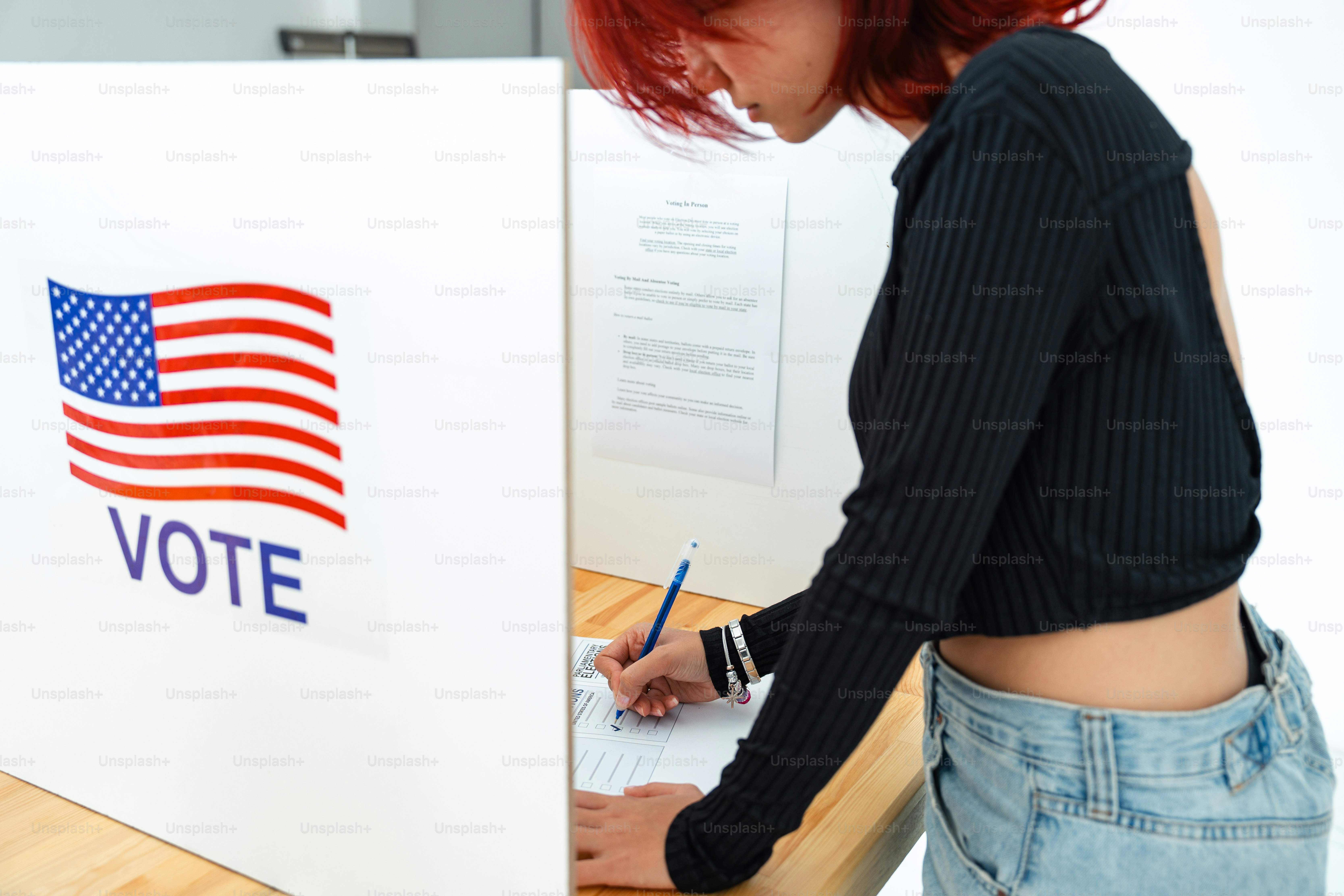 A woman writing on a piece of paper in front of a vote sign photo ...