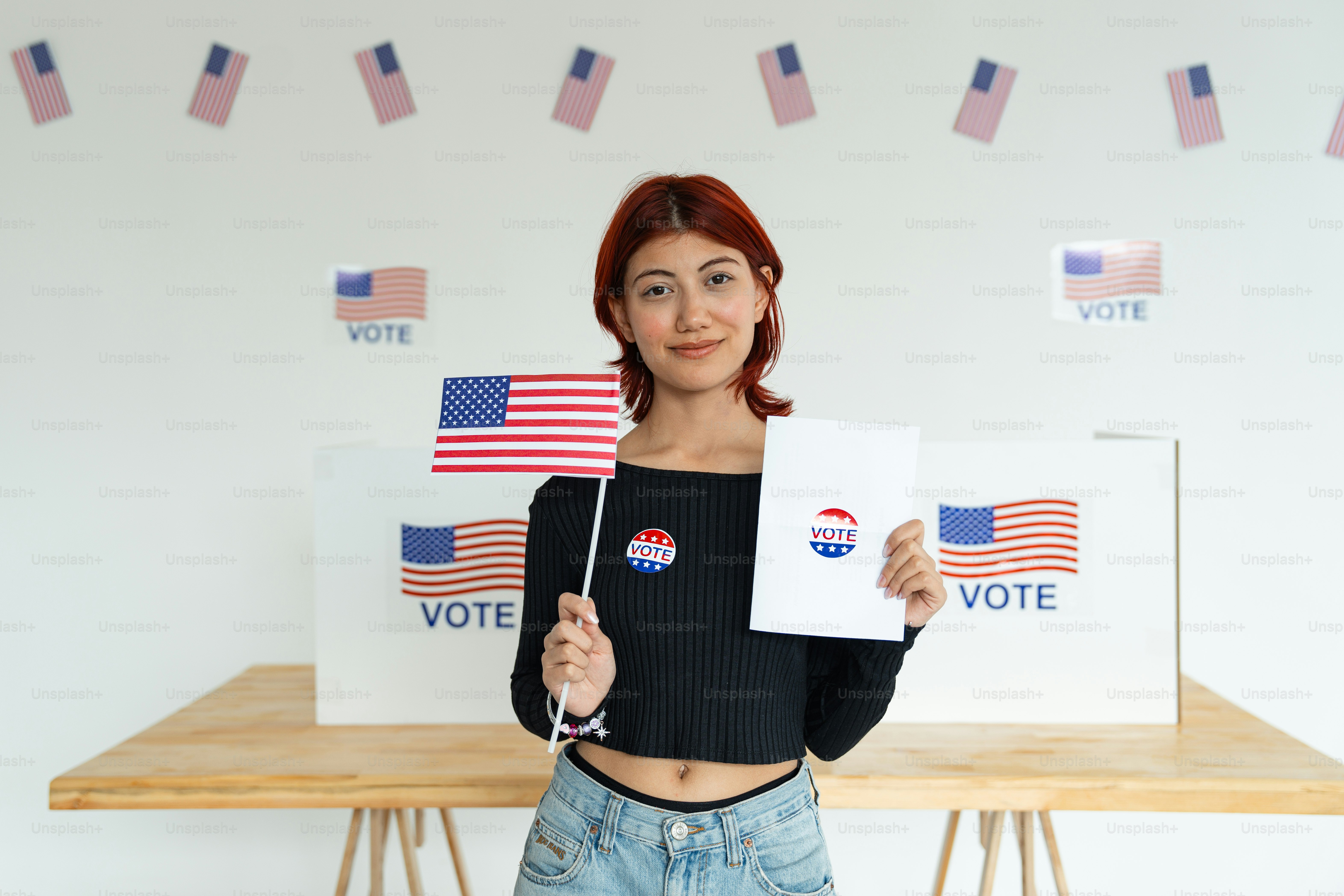 A woman holding a voting sign in front of a voting booth photo – Vote ...