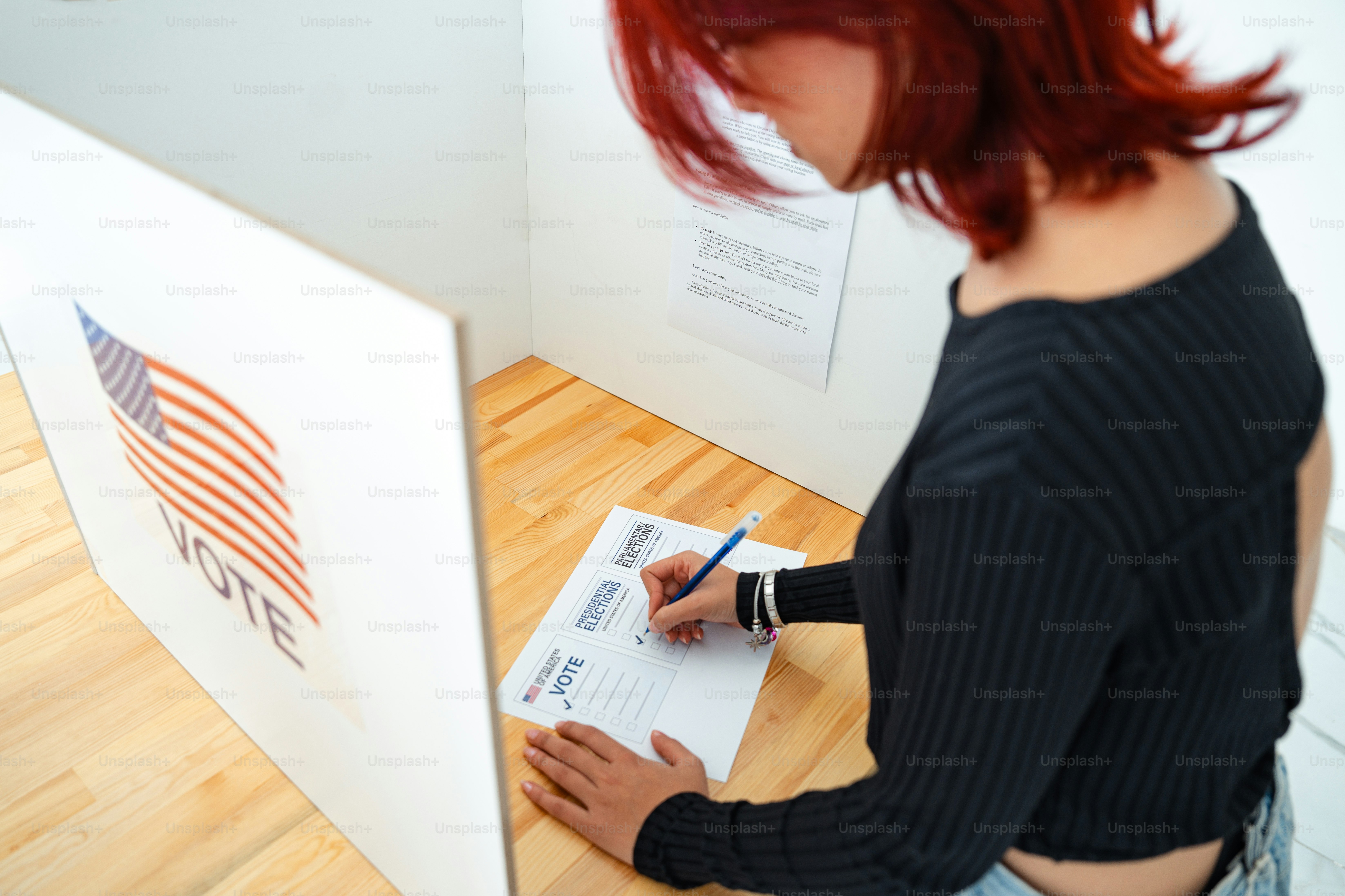 A woman holding a voting sign in front of a voting booth photo – Vote ...