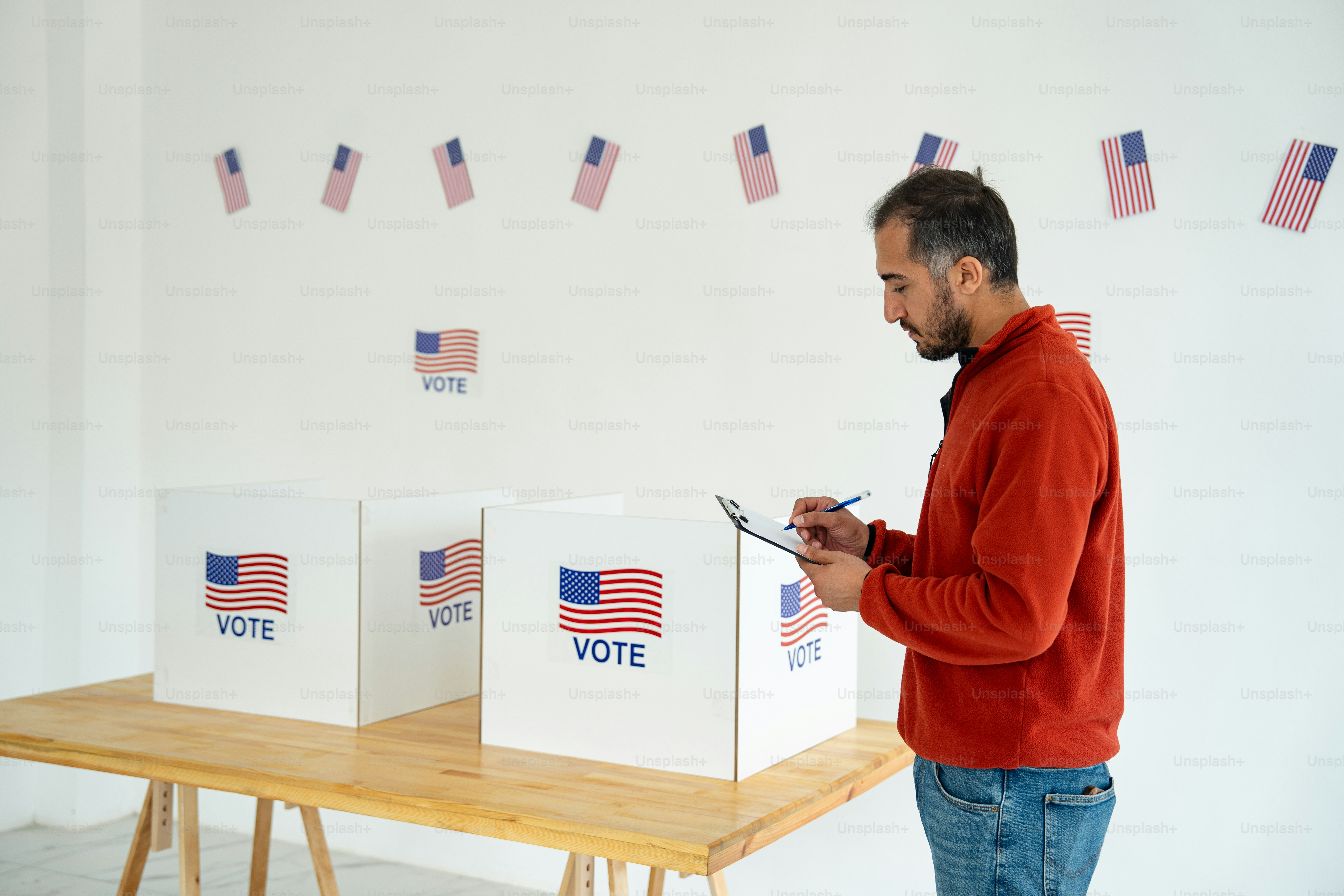 A man standing in front of a table with voting boxes on it