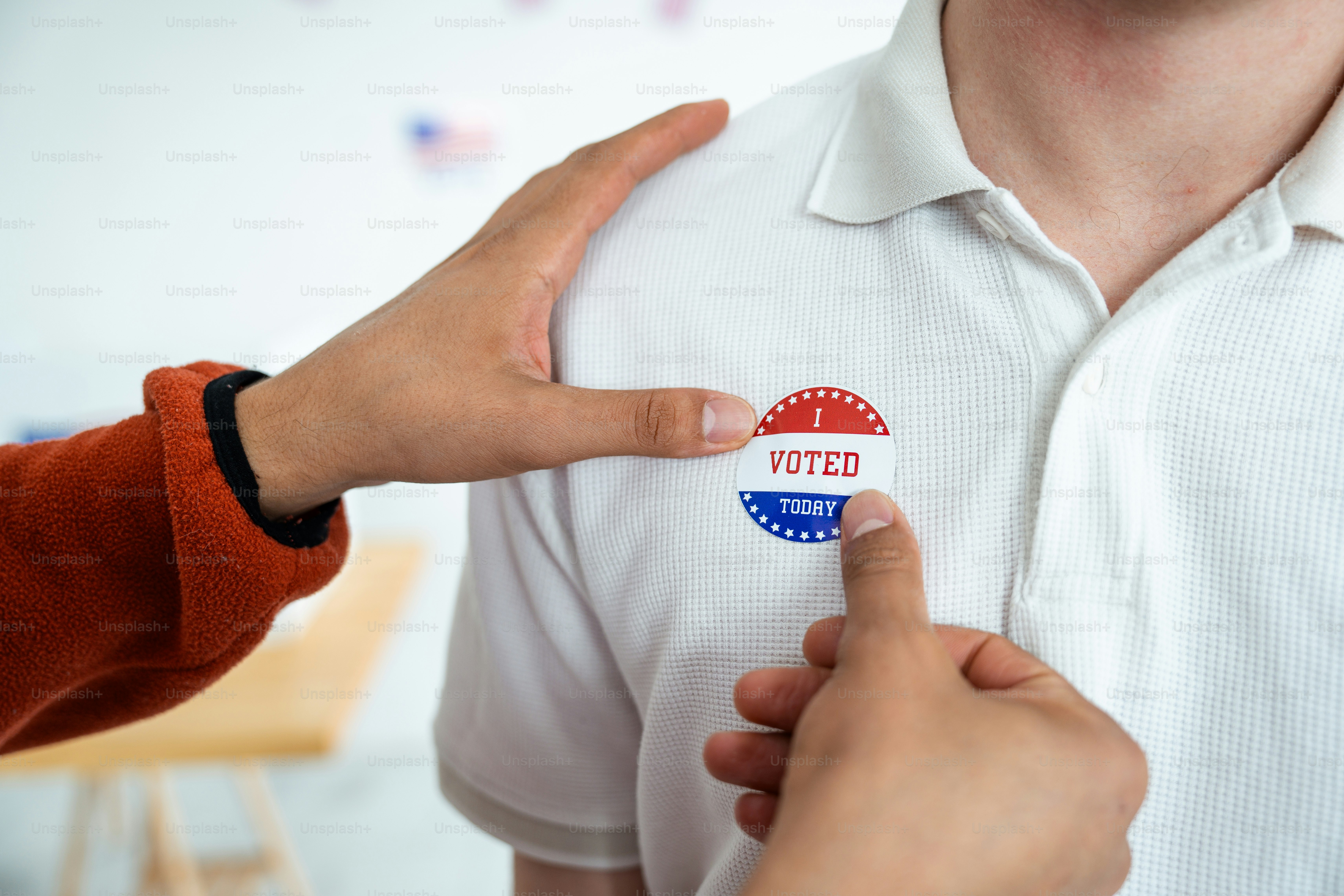 Una persona que pone una calcomanía en la camisa de otra persona