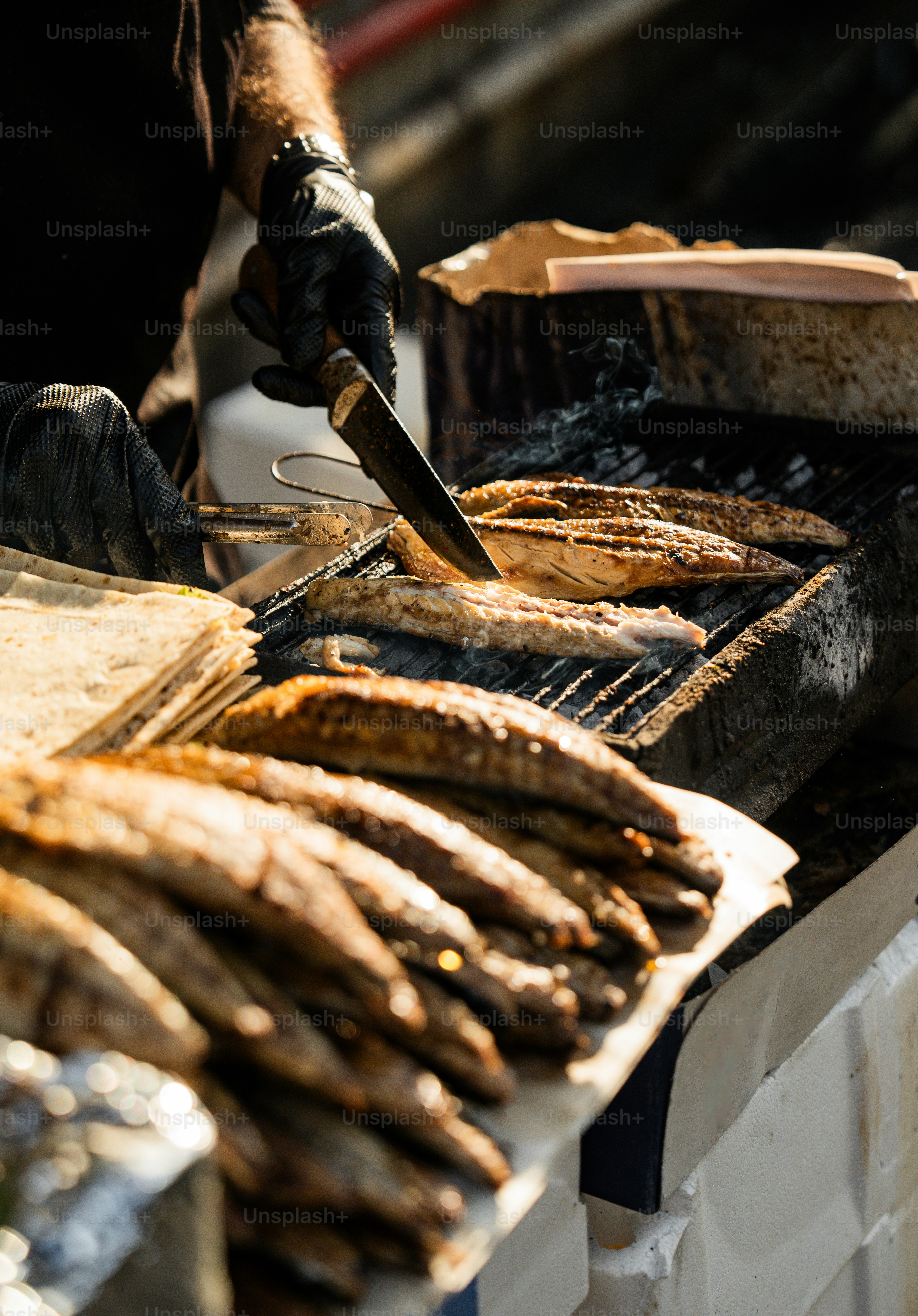 A man grilling fish on a grill with a knife