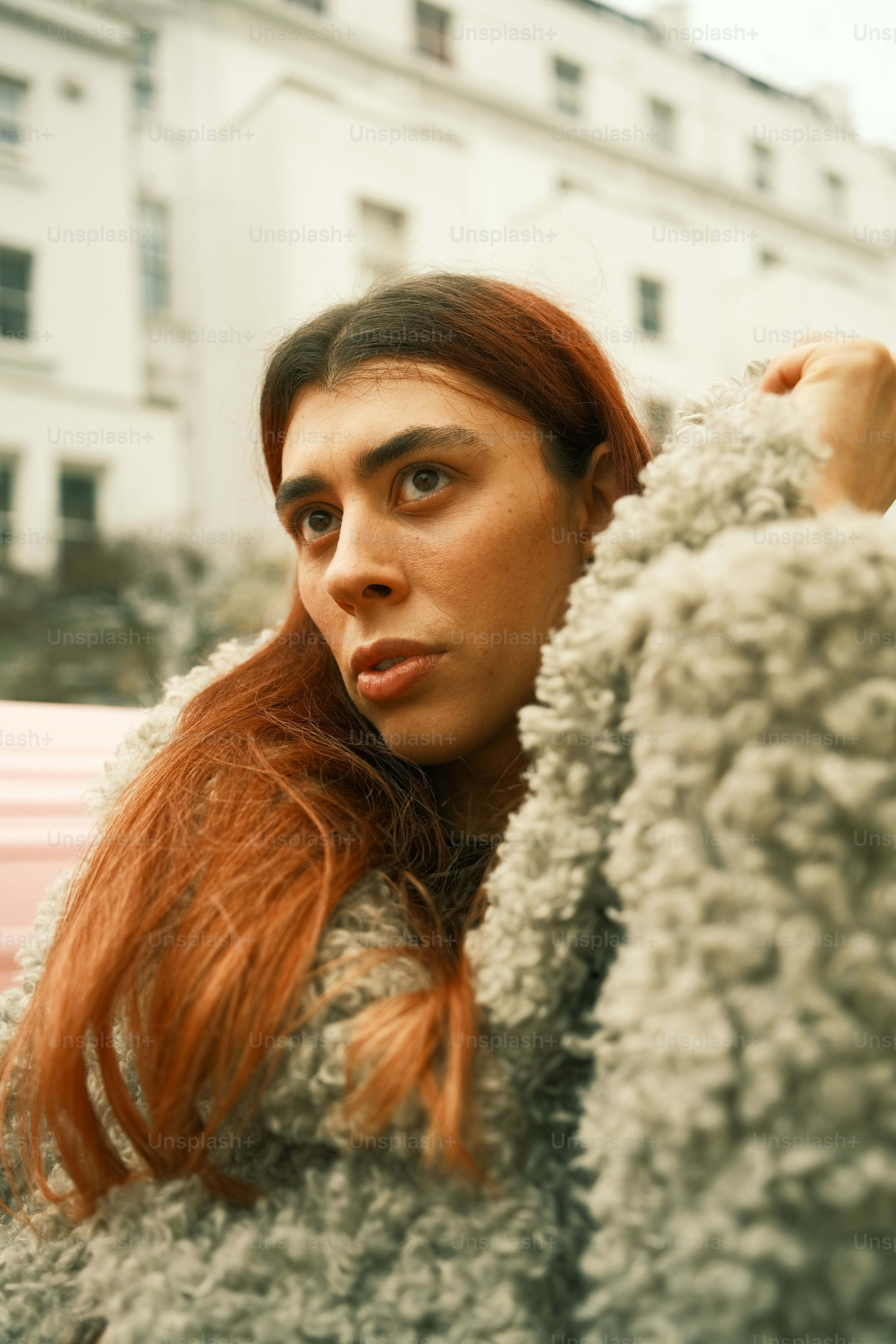 Una mujer con el pelo largo y rojo parada frente a un coche