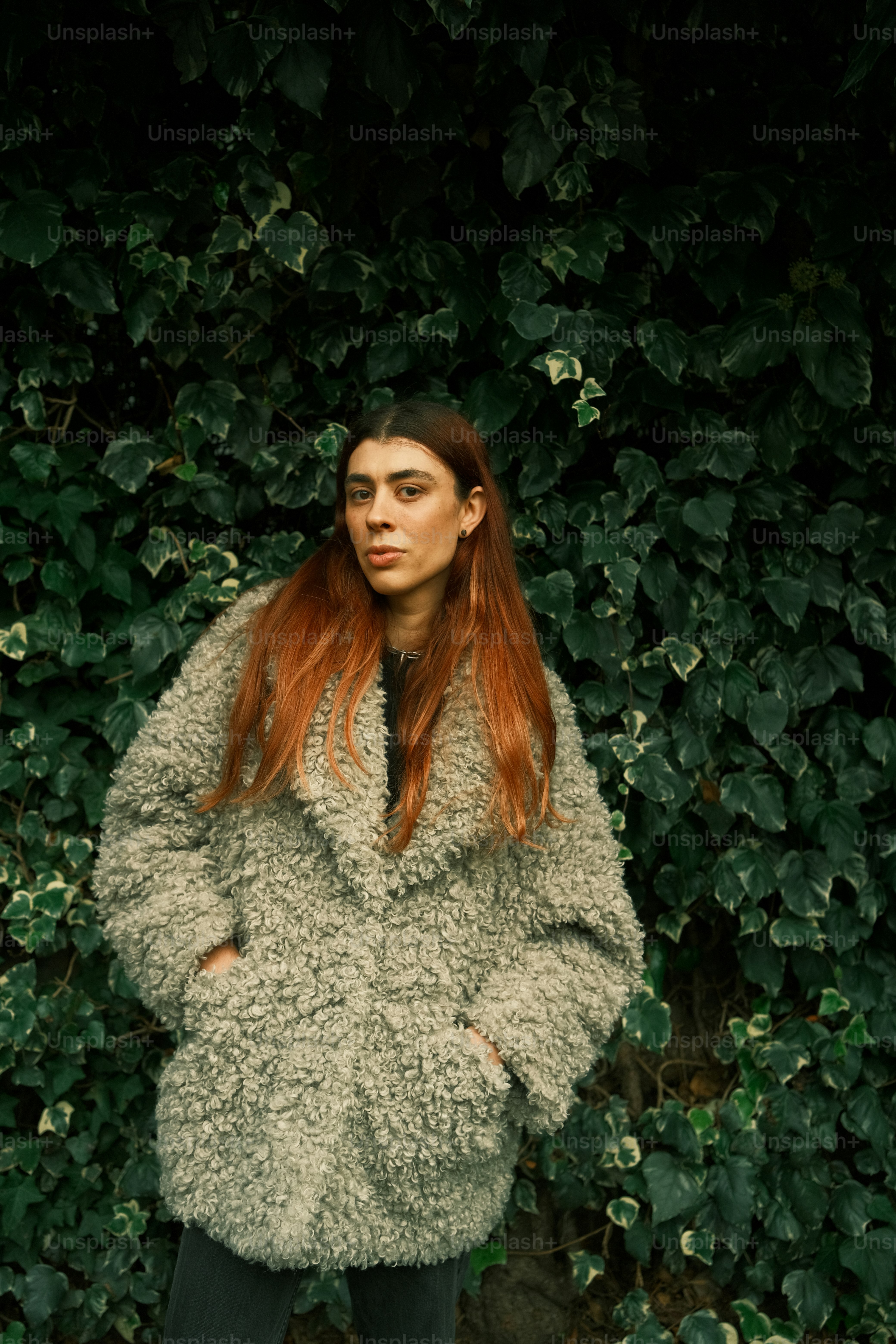 A woman with red hair standing in front of a bush photo – Portrait ...