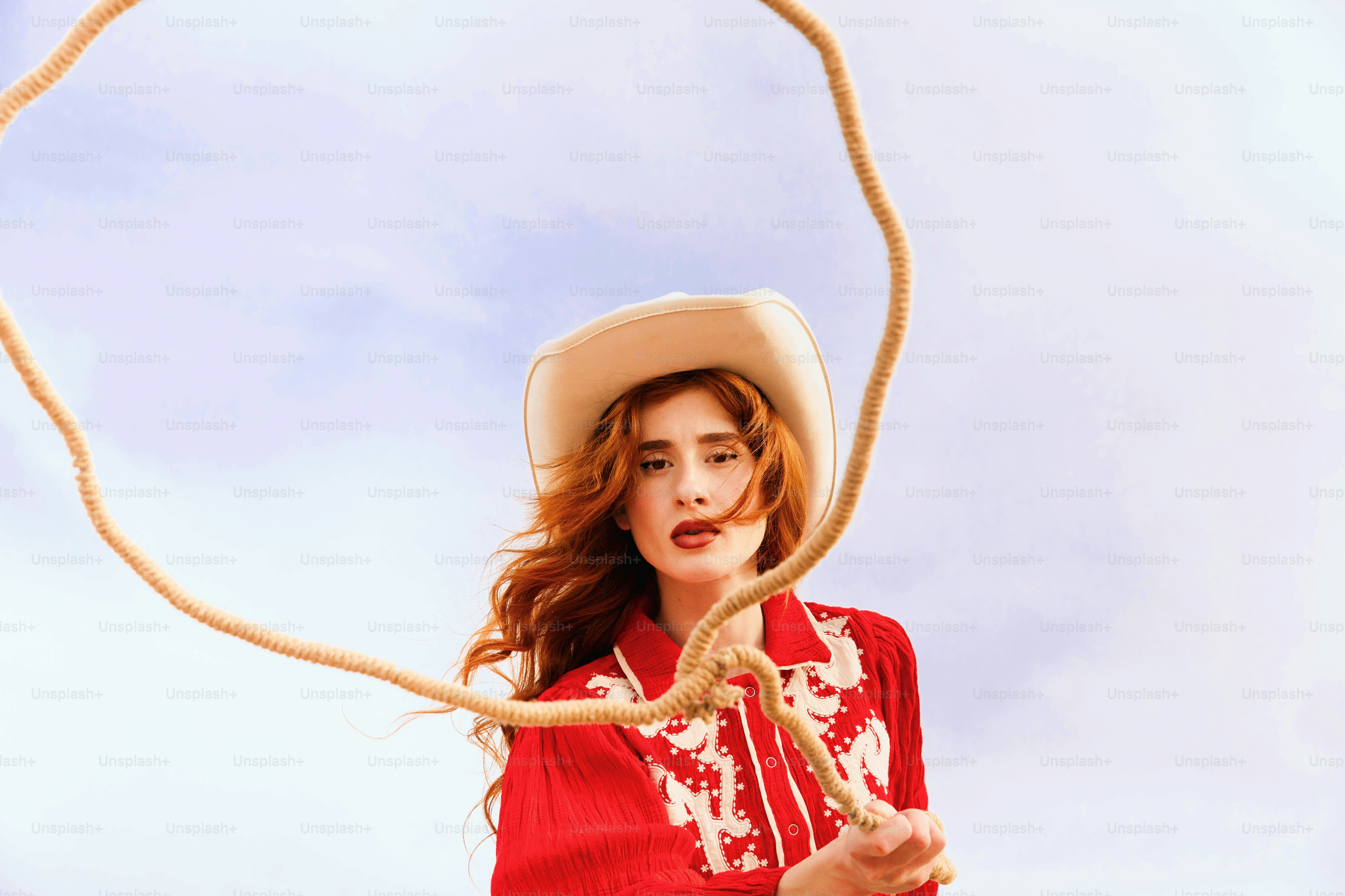 A woman in a red shirt and hat holding a rope