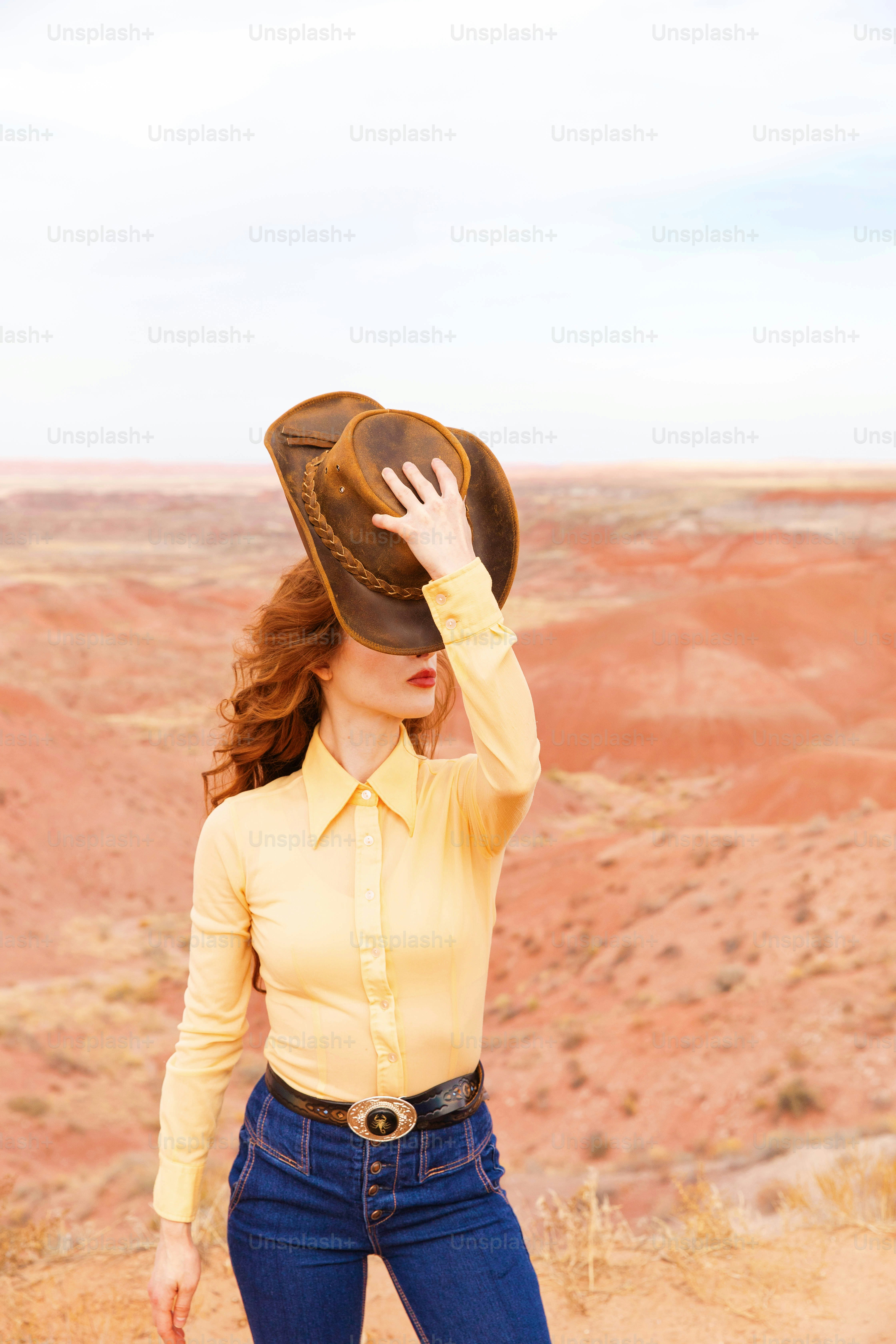 Une femme en chemise jaune et jean avec un chapeau sur la tête