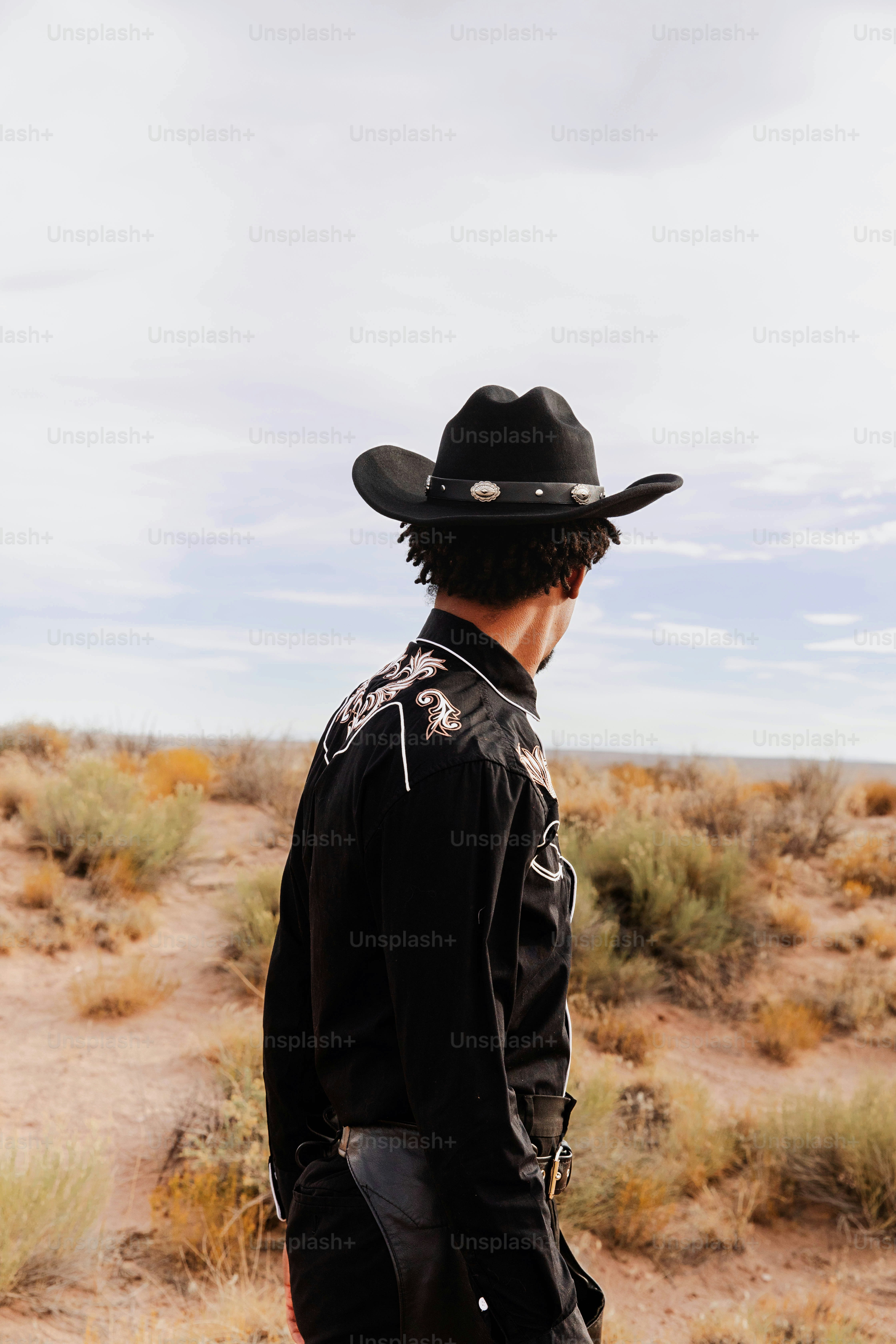 A man in a cowboy hat standing in the desert