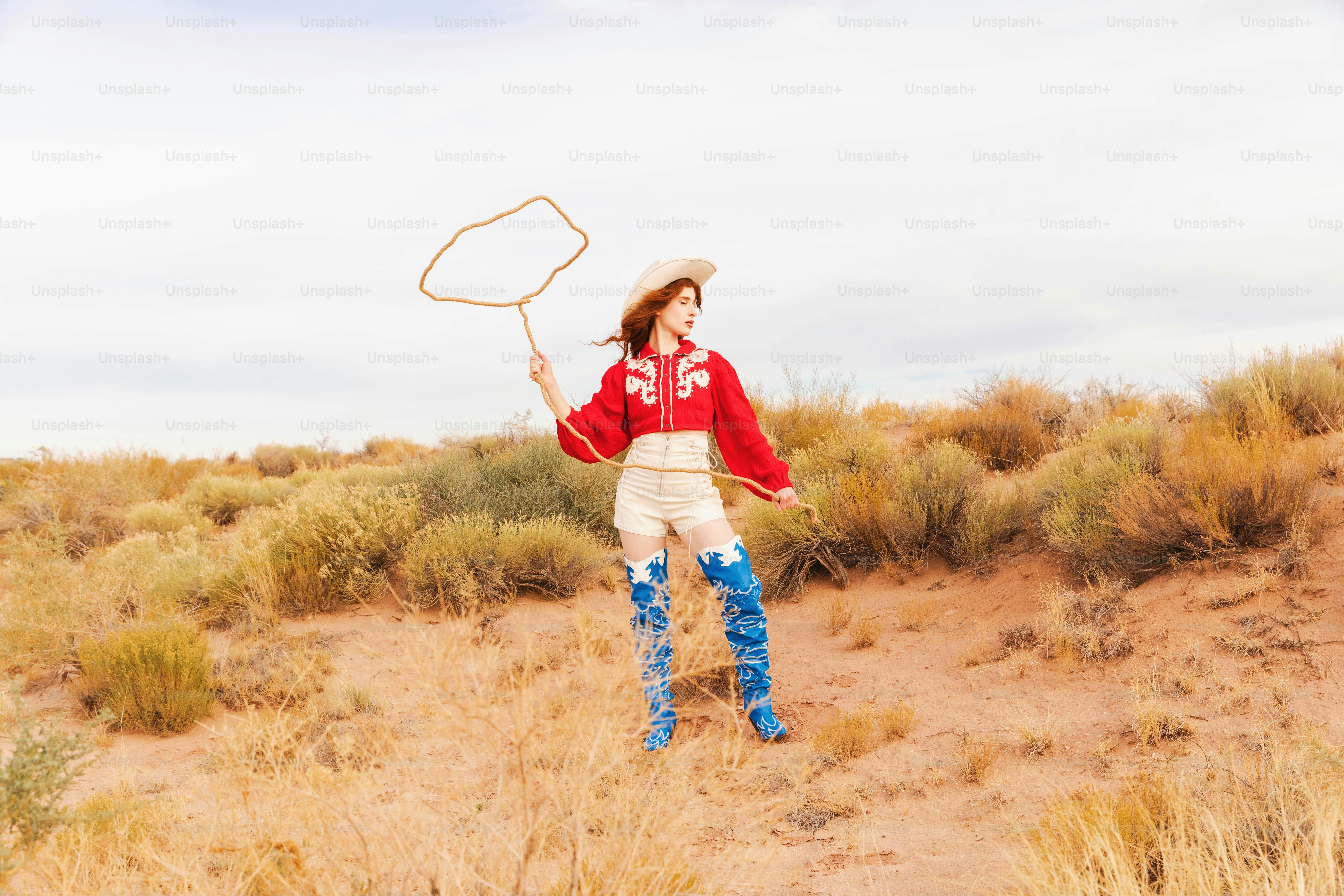 A woman in boots and a hat holding a tennis racket
