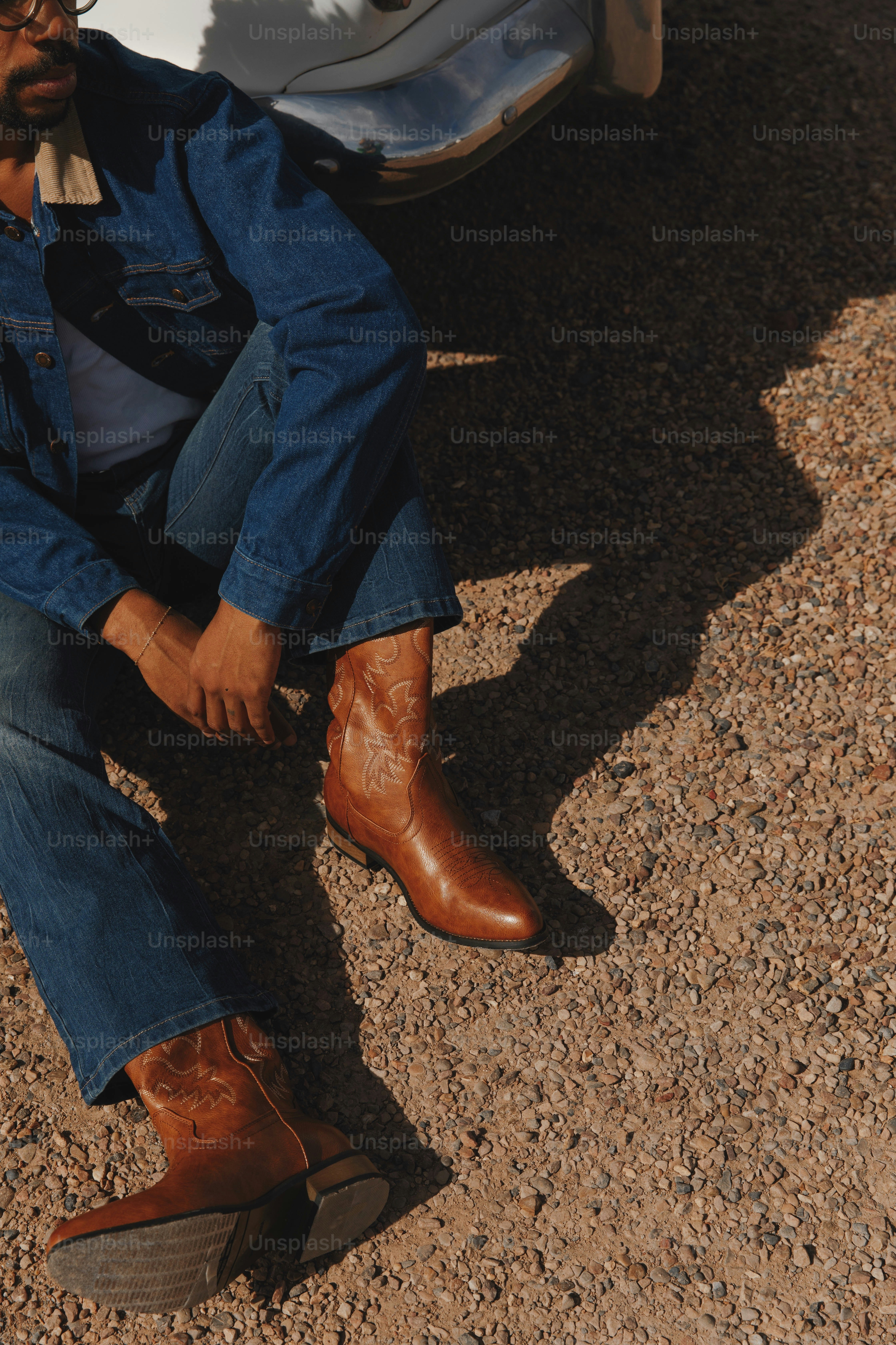 A man sitting on the ground next to a car
