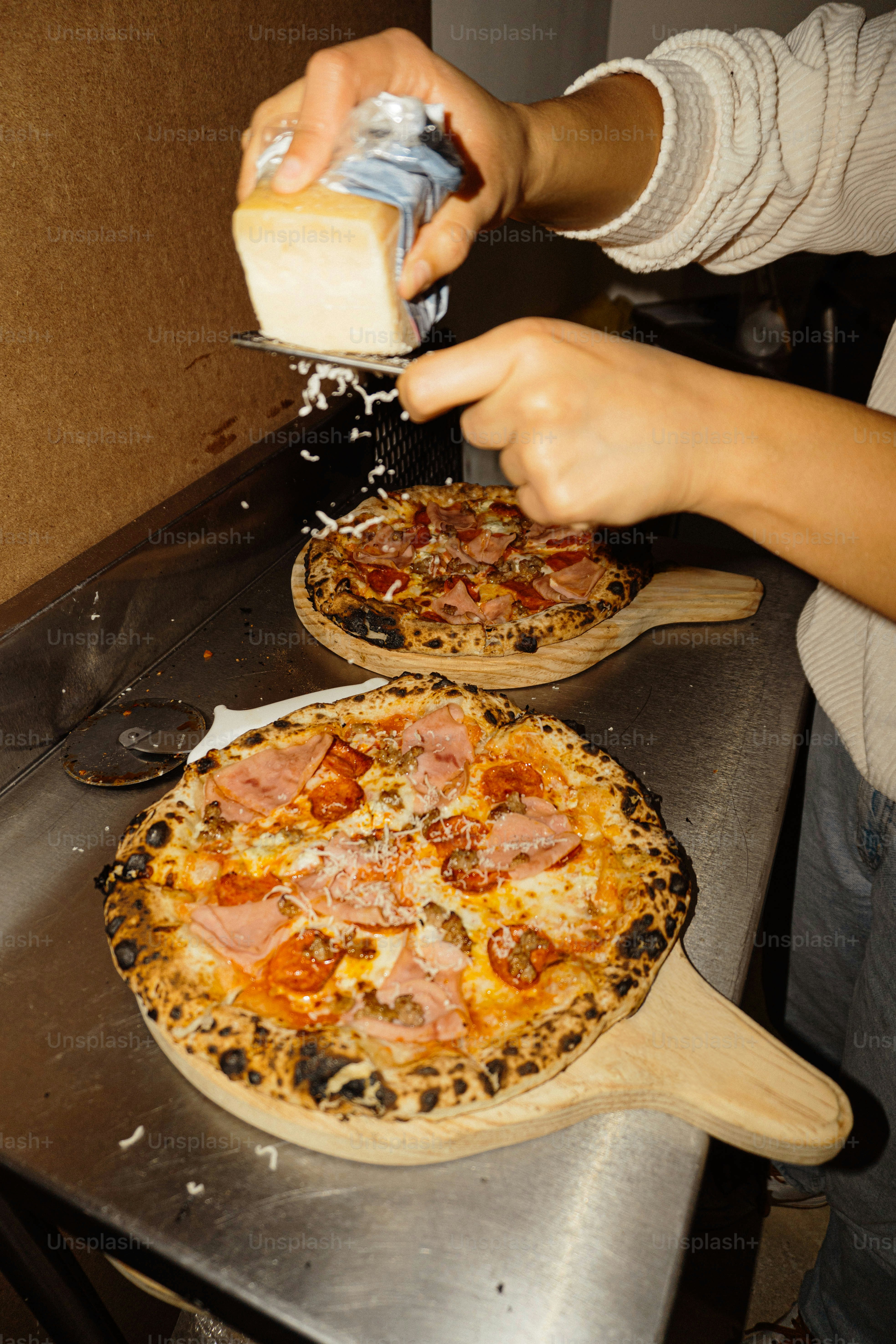 A person is putting cheese on a pizza