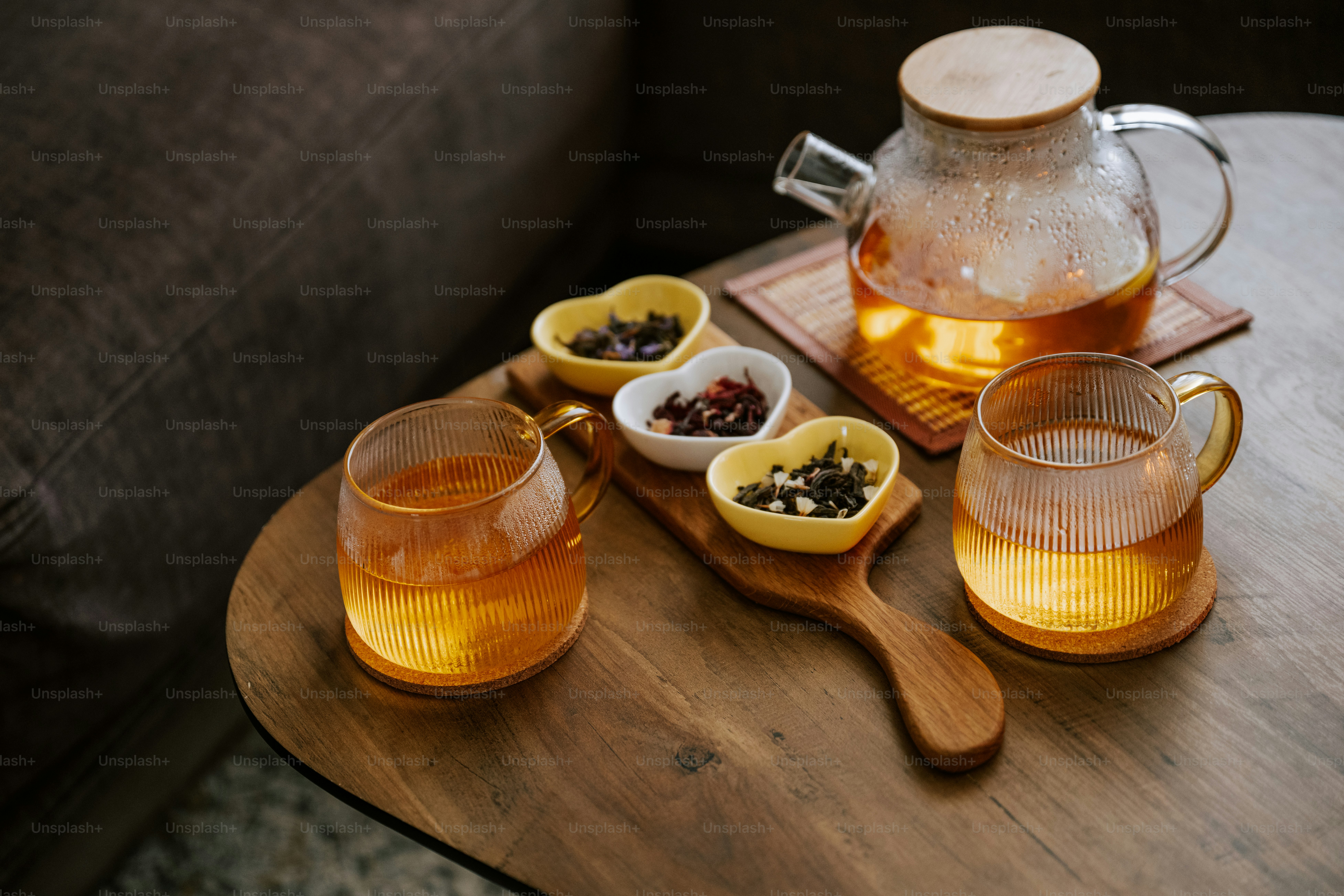 A wooden table topped with cups and a pitcher of tea