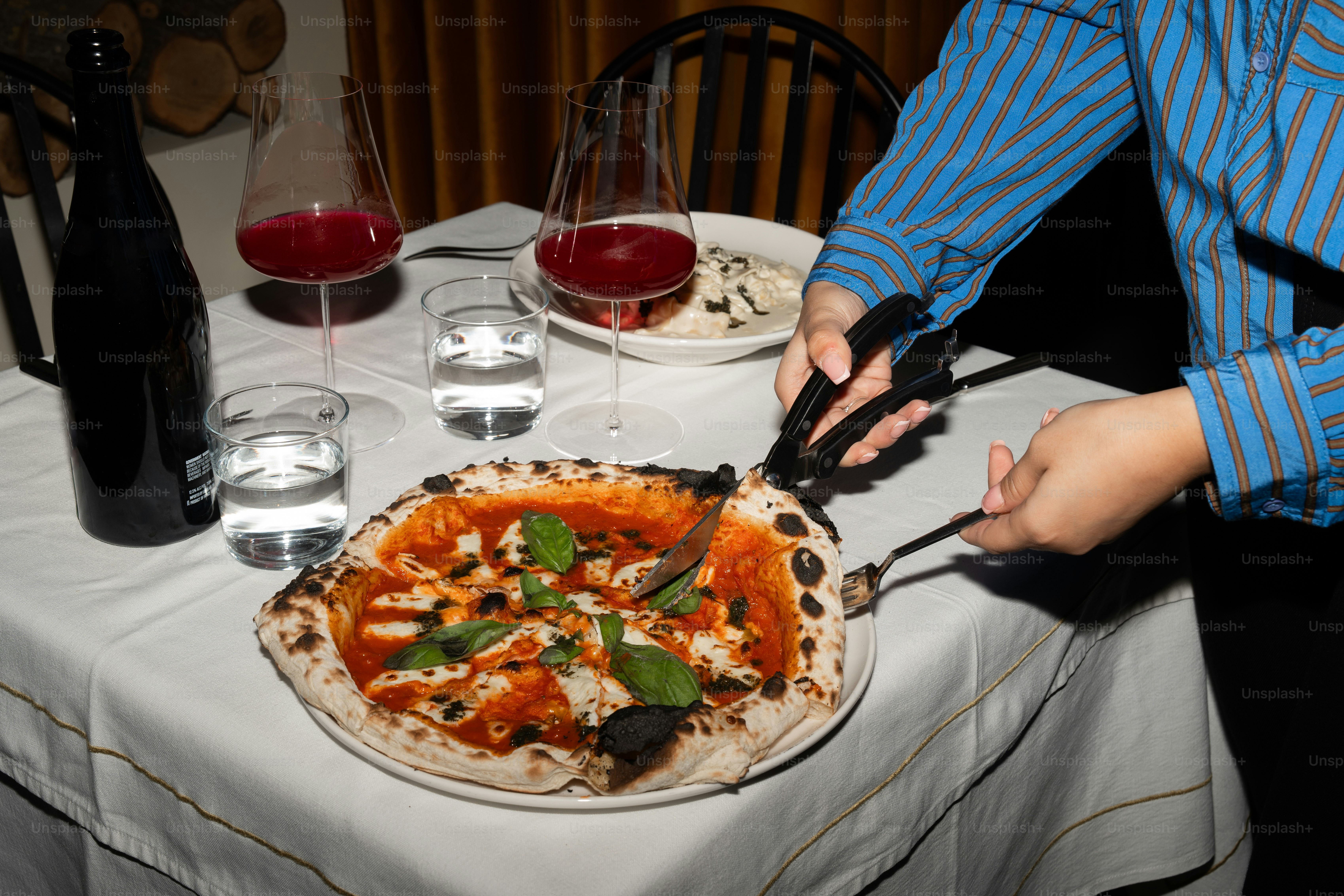 A person cutting a pizza on a table